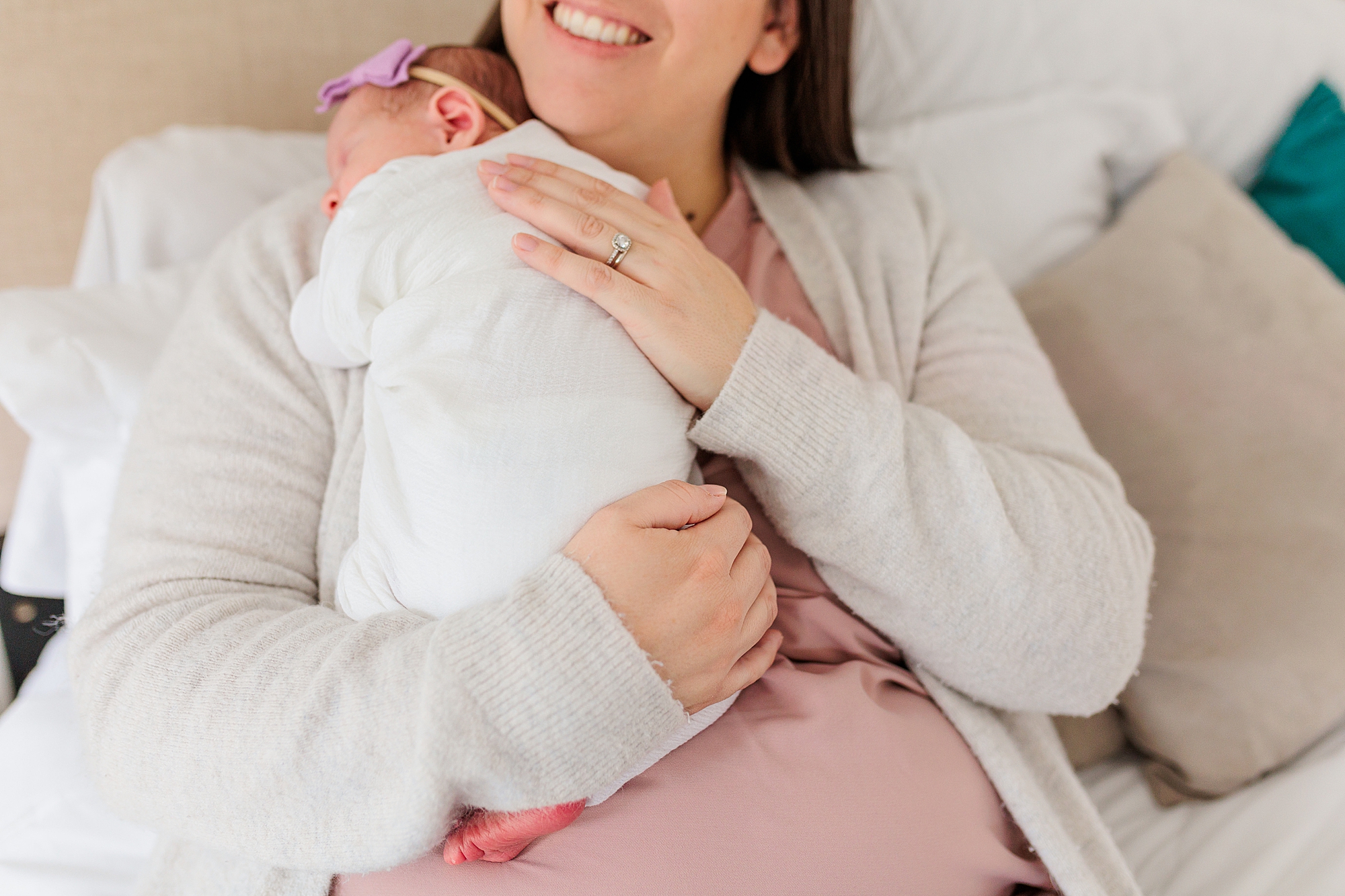 mom holds newborn daughter on shoulder during lifestyle newborn session