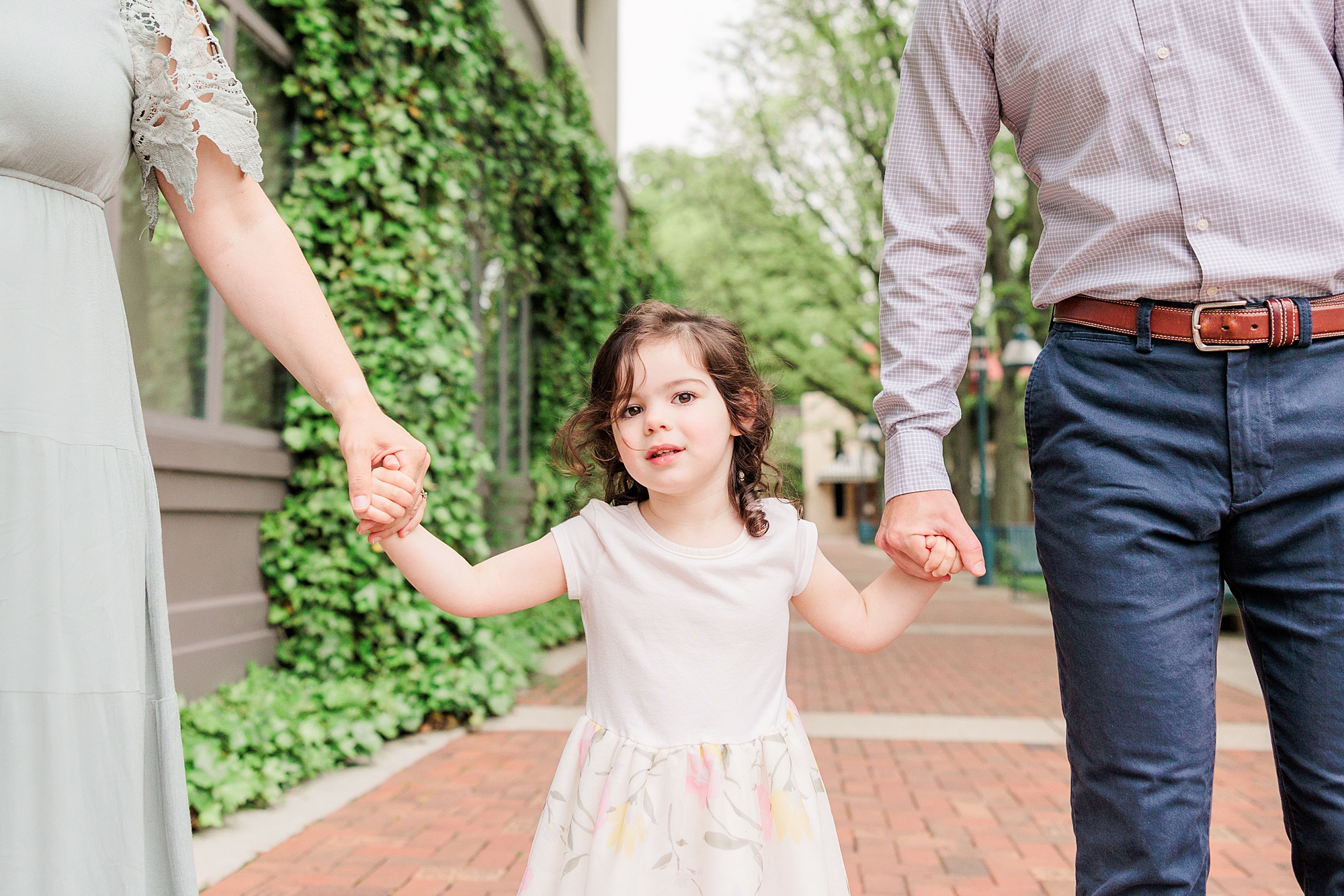 parents hold daughter's hand walking through Columbia MD park