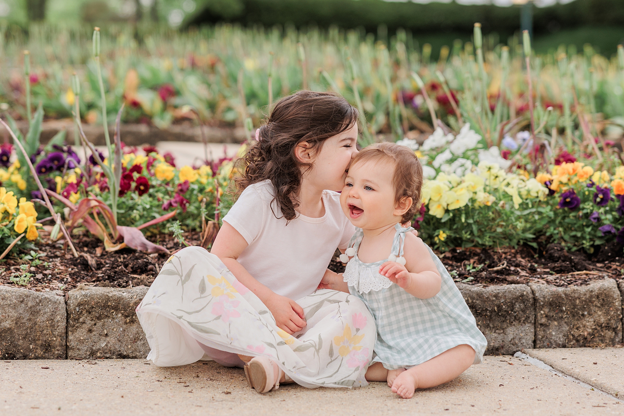 big sister whispers to little sister during family portraits in Maryland