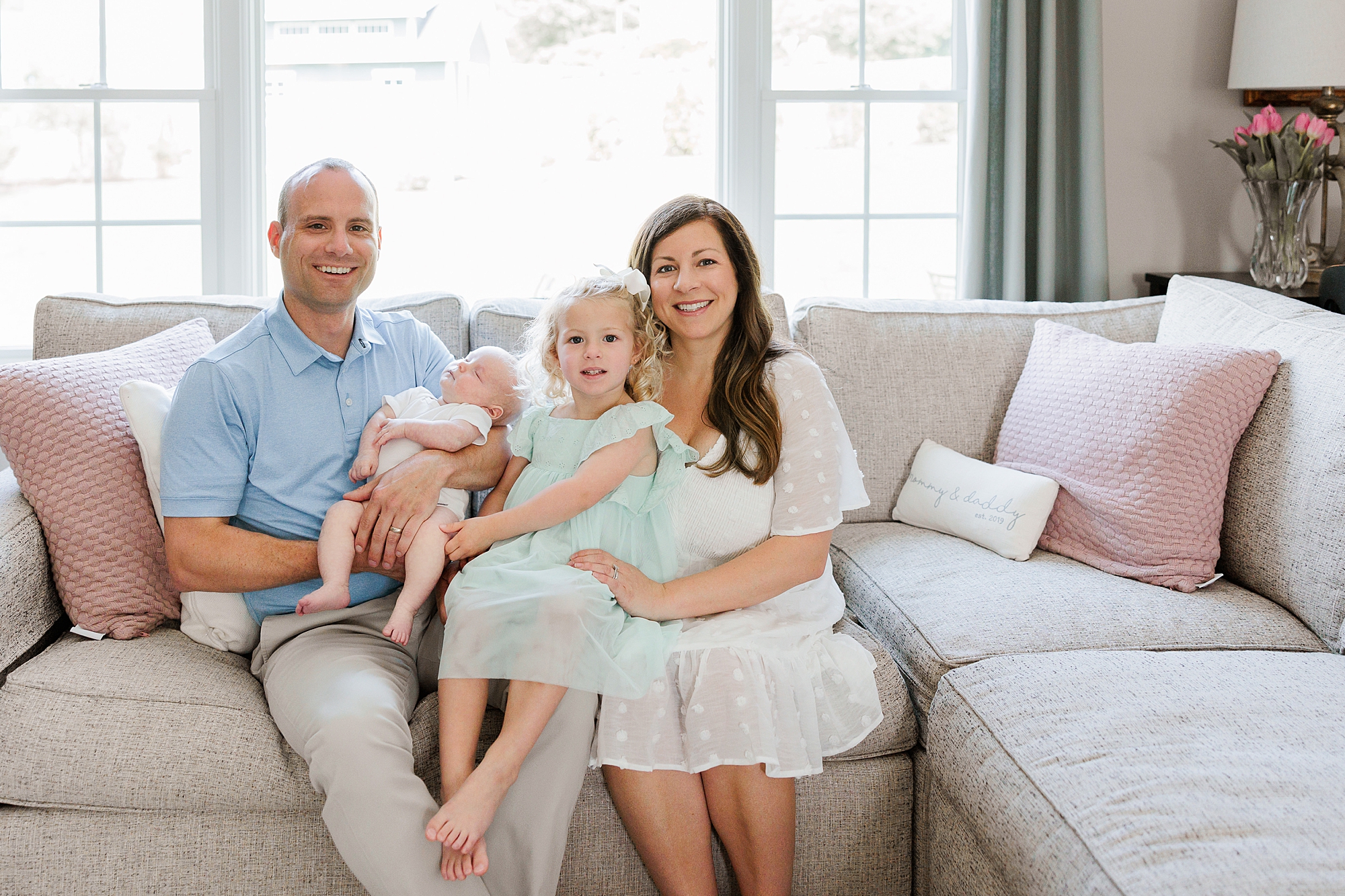 family sits on couch in Maryland home during lifestyle newborn session
