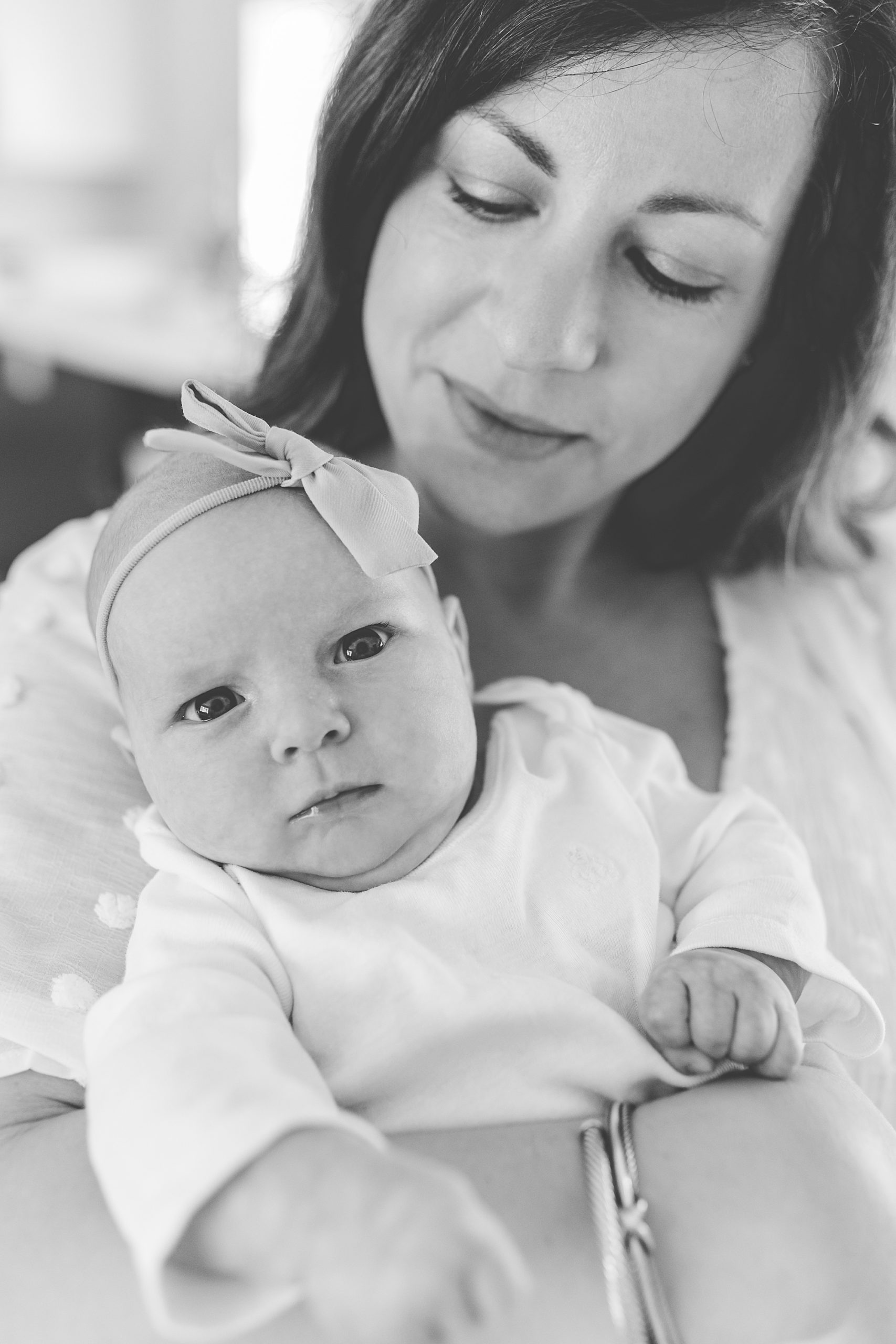 mom looks at baby girl with bow on head during lifestyle newborn session