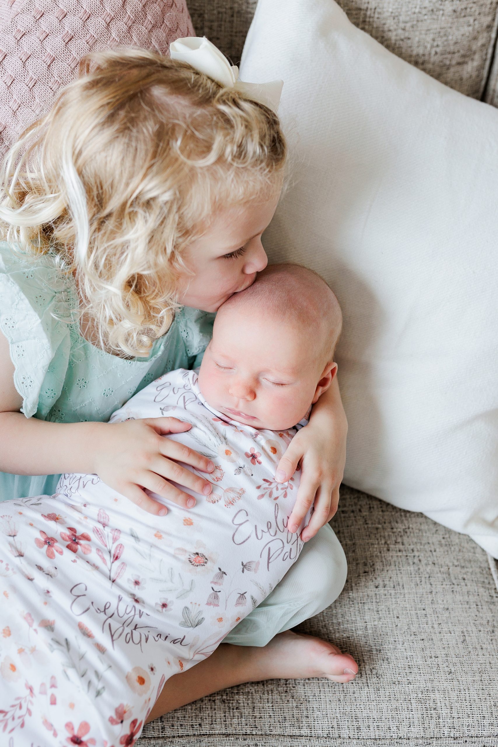toddler kisses baby sister on head during lifestyle newborn session