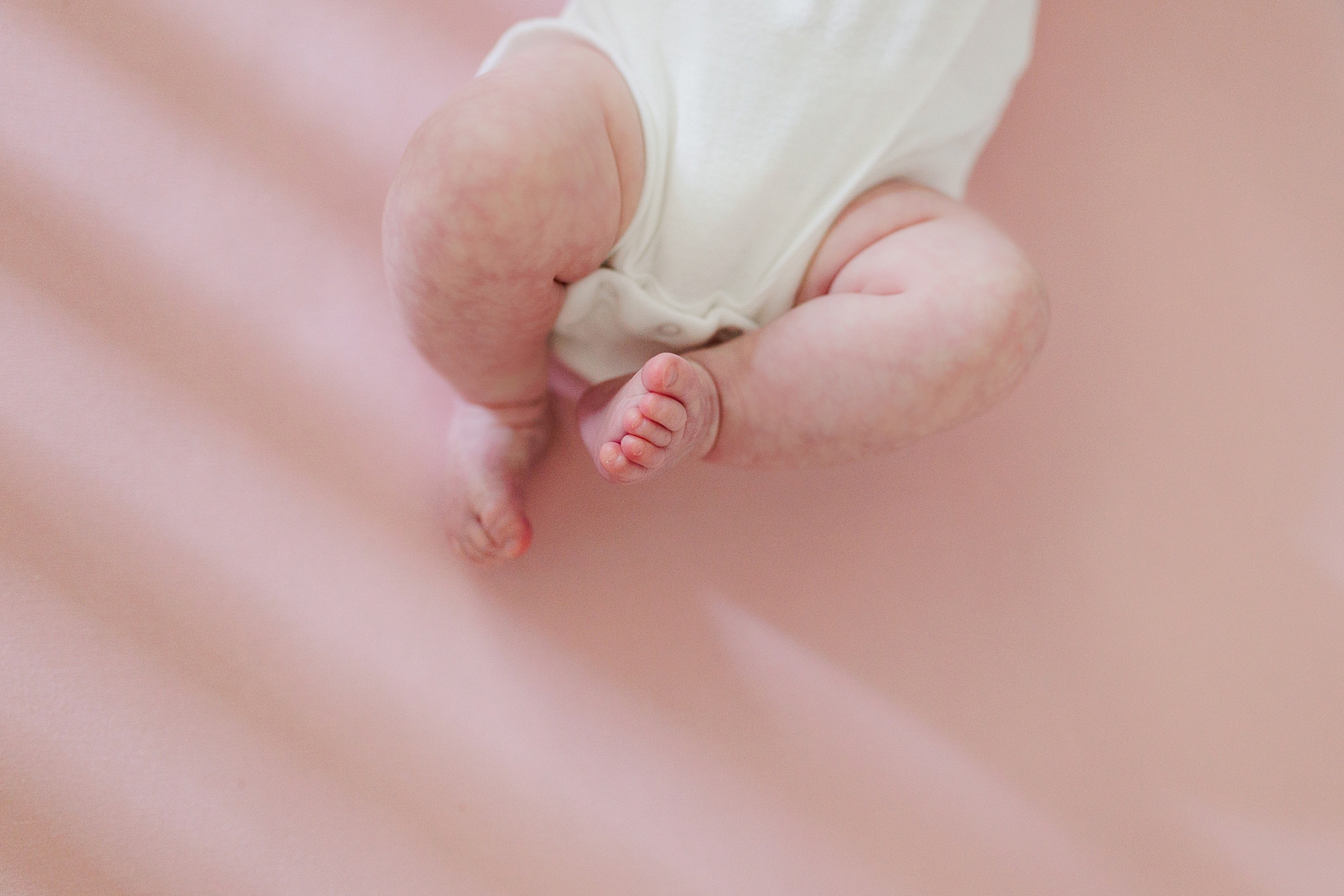 baby girl lays on pink blanket in crib during lifestyle newborn session
