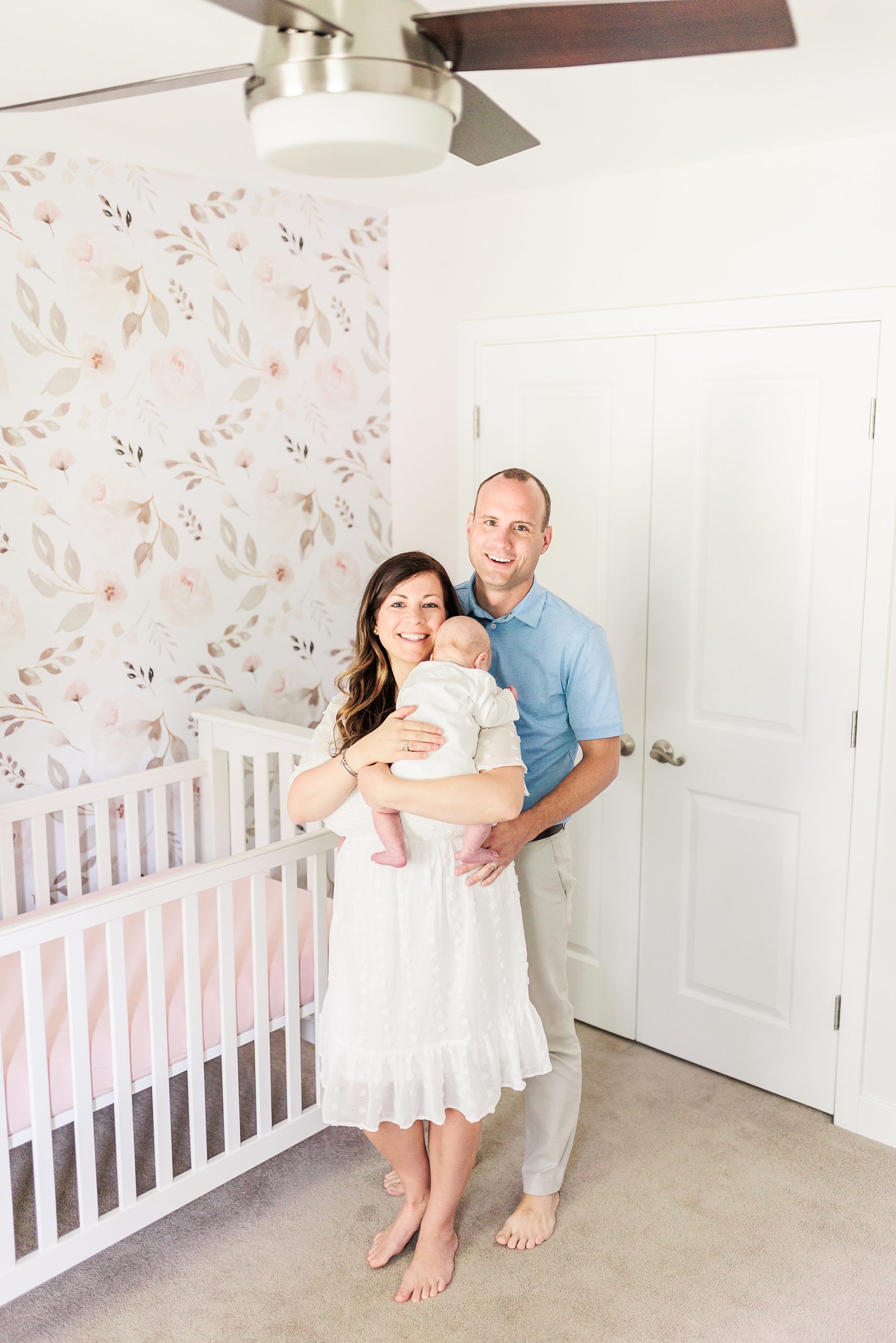 parents stand with baby girl in nursery during lifestyle newborn session