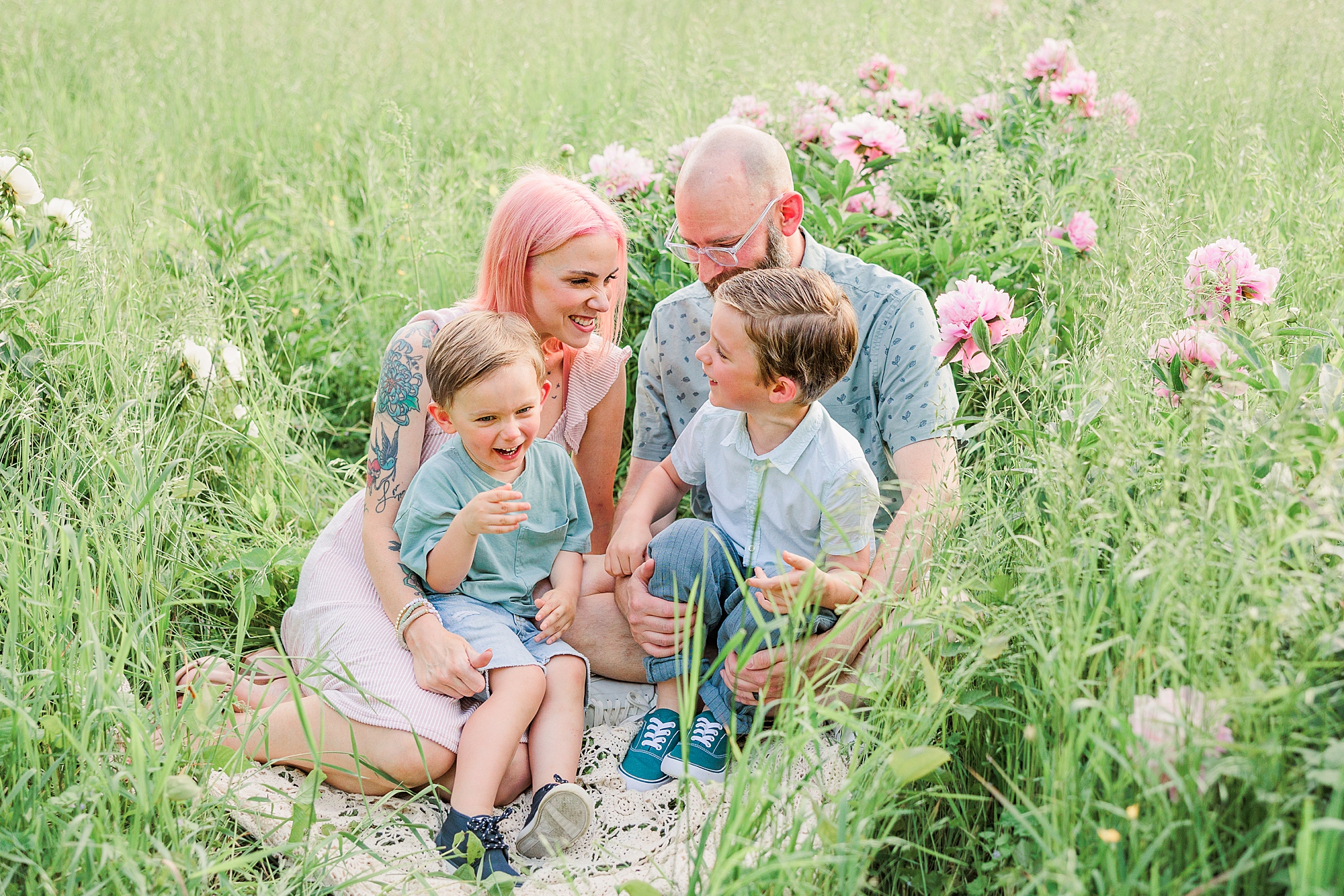 family of four sits in field of peonies during Seneca Creek Park parenthood portraits