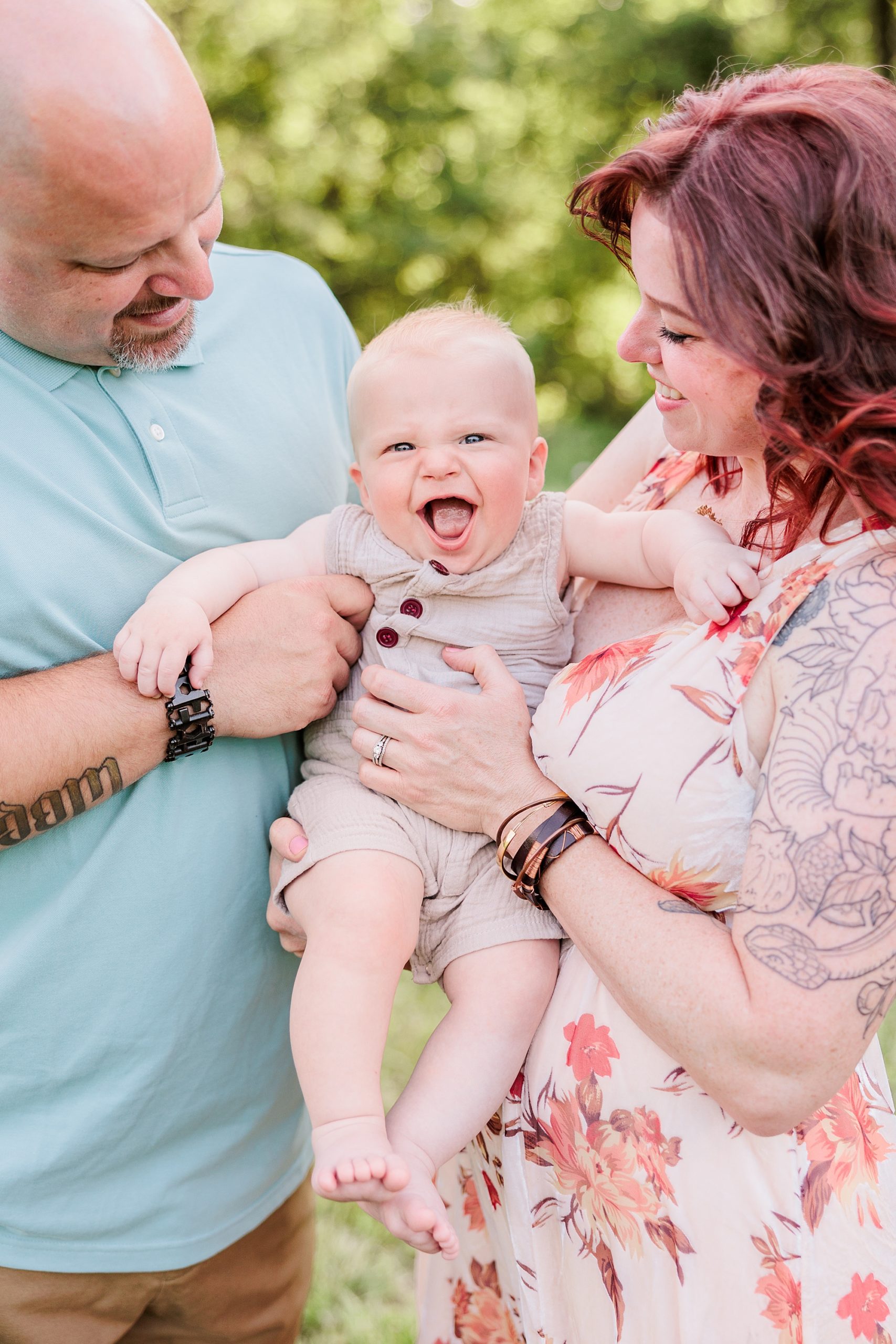 baby laughs between parents during family photos in Maryland field