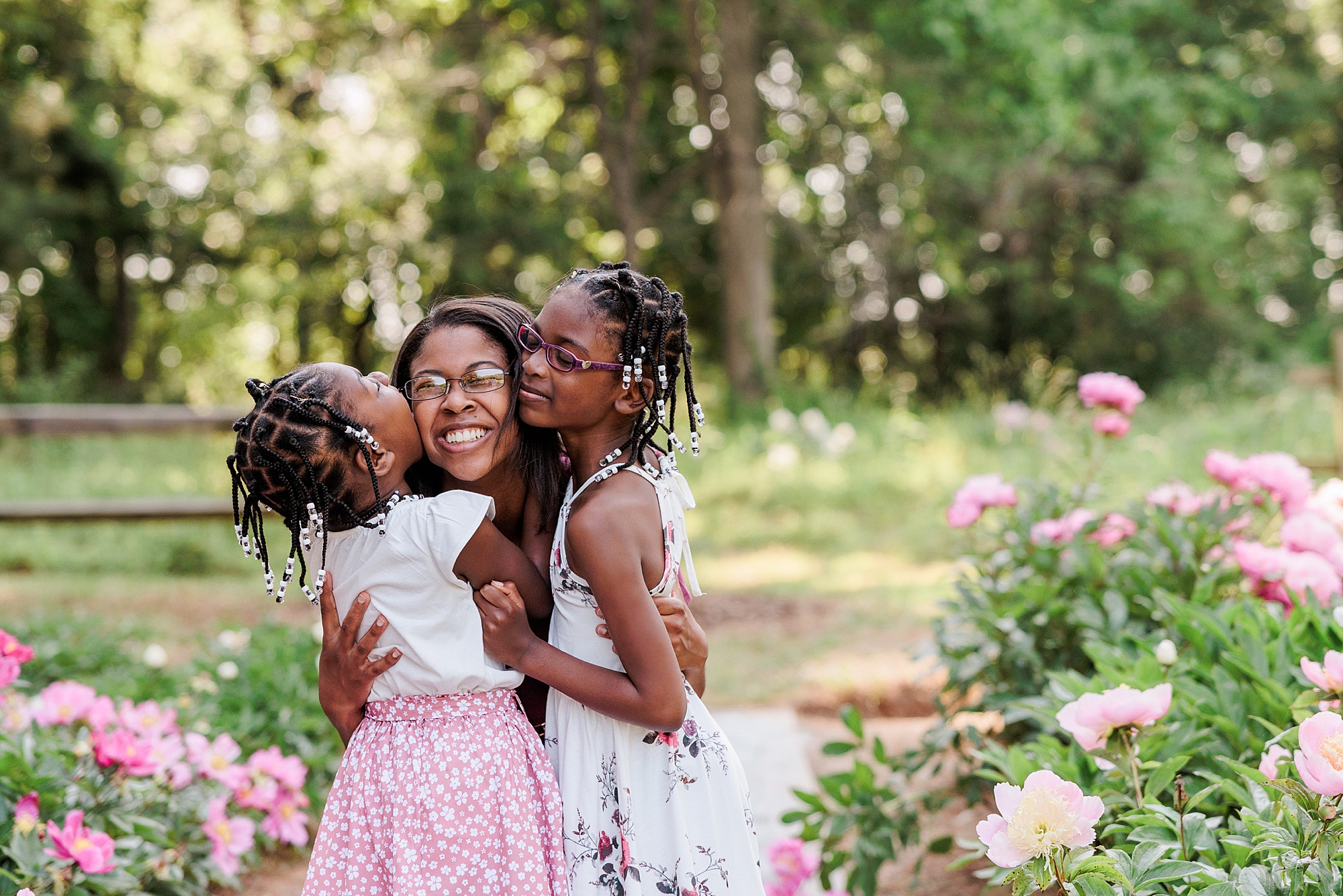 girls kiss mom's cheek during Seneca Creek Park parenthood portraits