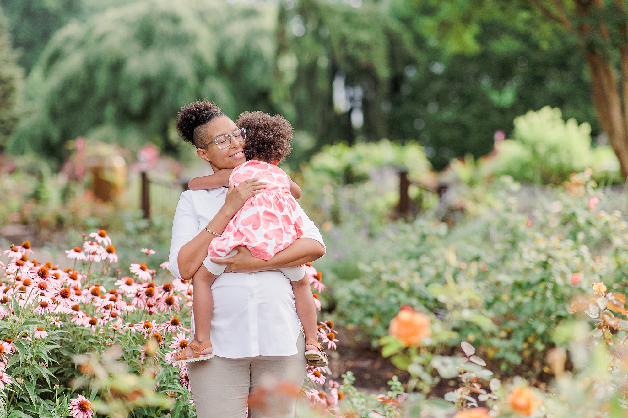 woman holds daughter during Bethesda maternity portraits in gardens