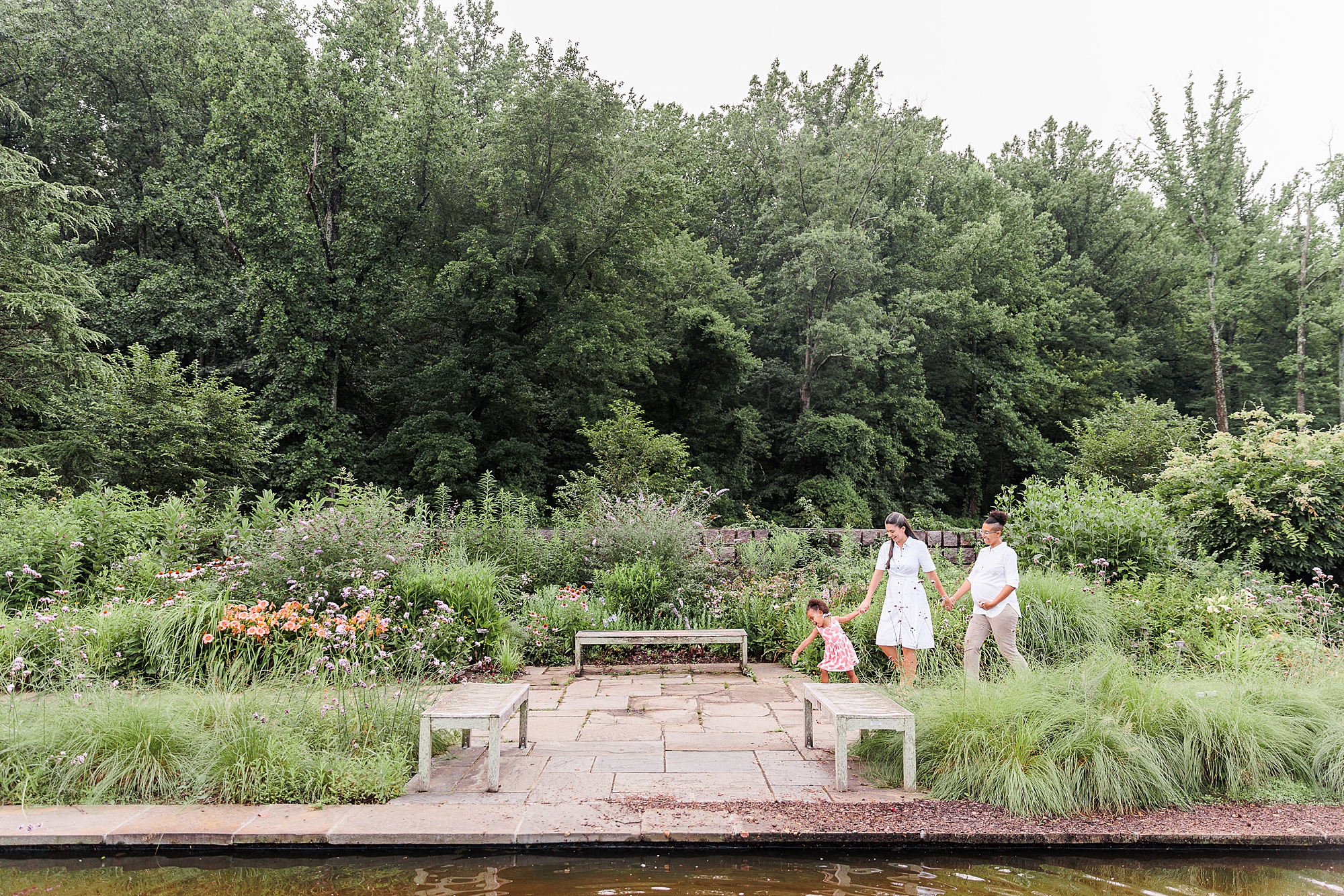 family walks through gardens during Bethesda maternity portraits