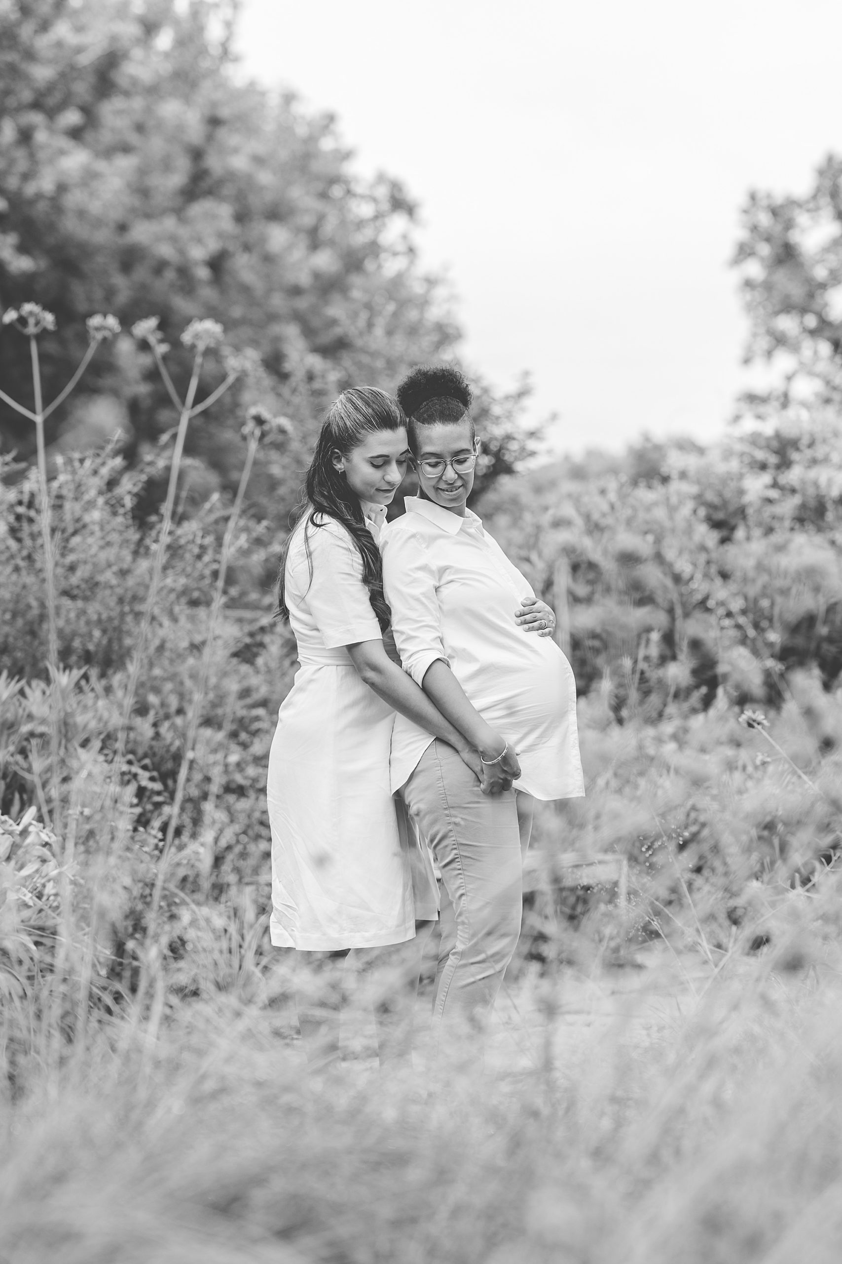 woman hugs wife from behind during Bethesda maternity portraits