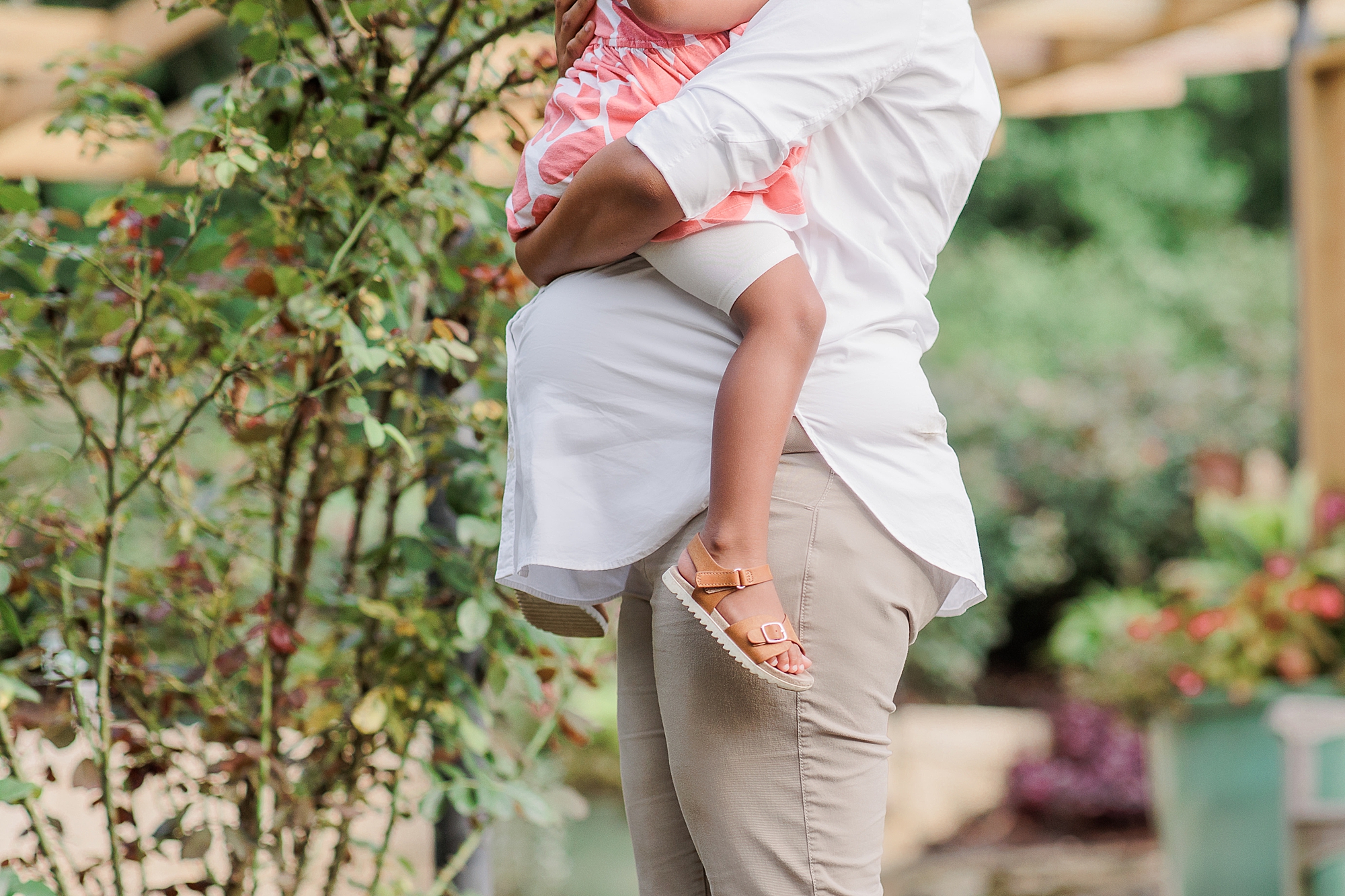 mom holds toddler on baby bump during Bethesda maternity portraits