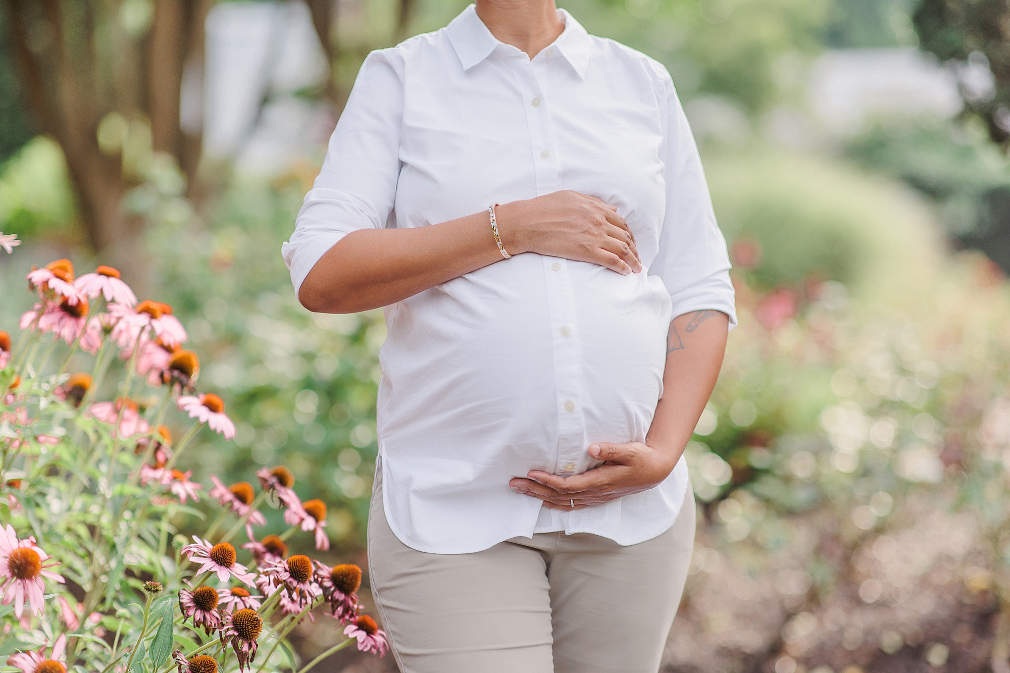 woman holds baby bump in white Oxford shirt during Bethesda maternity portraits