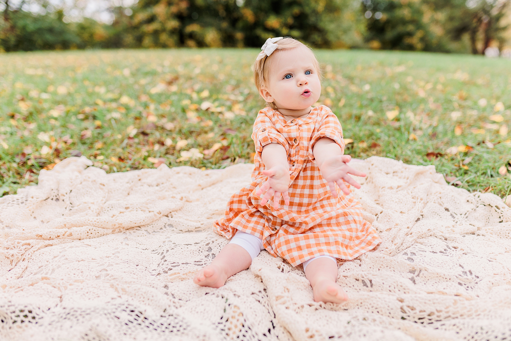 toddler plays on blanket in orange gingham dress