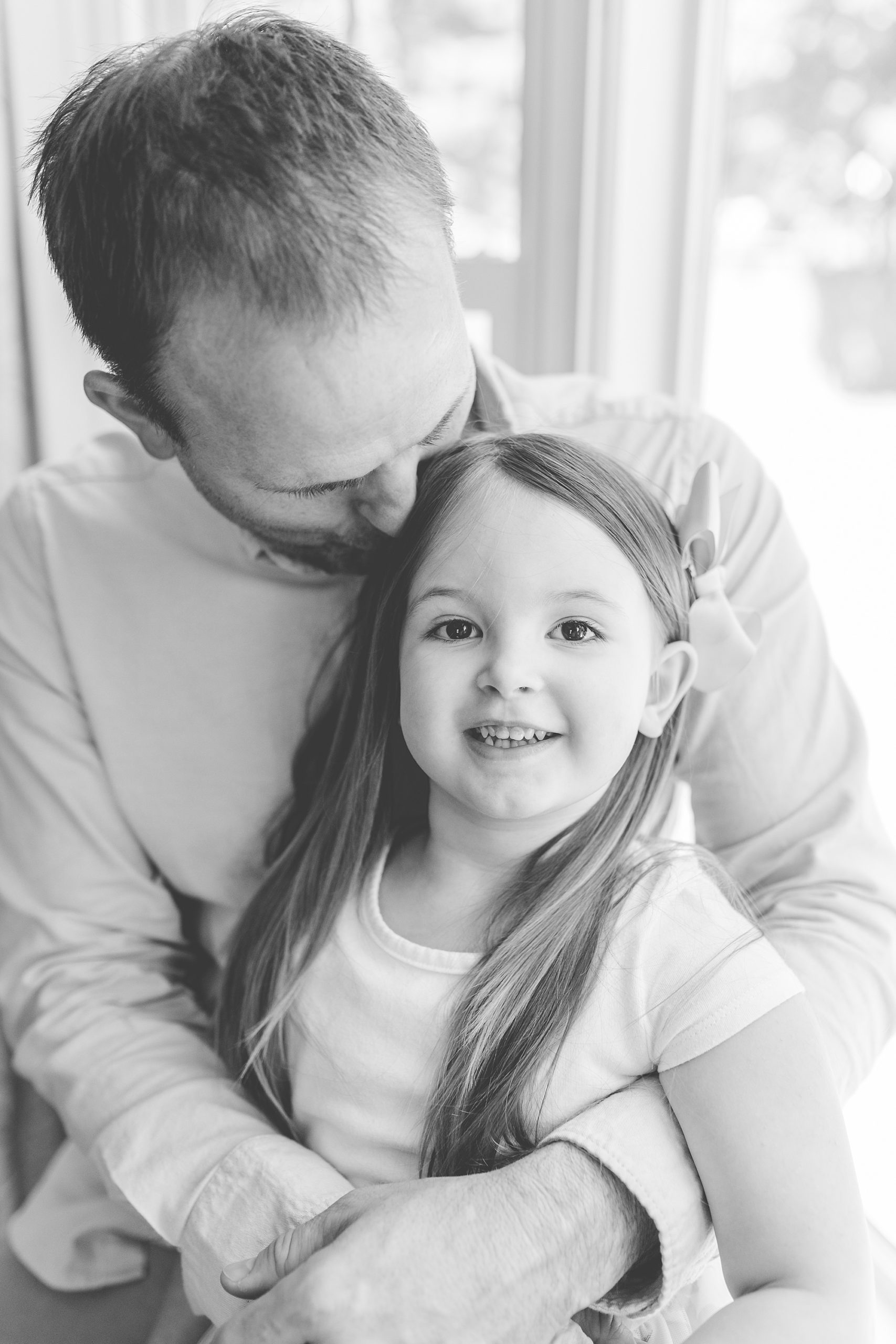 dad hugs toddler daughter in window seat during Annapolis MD lifestyle newborn session
