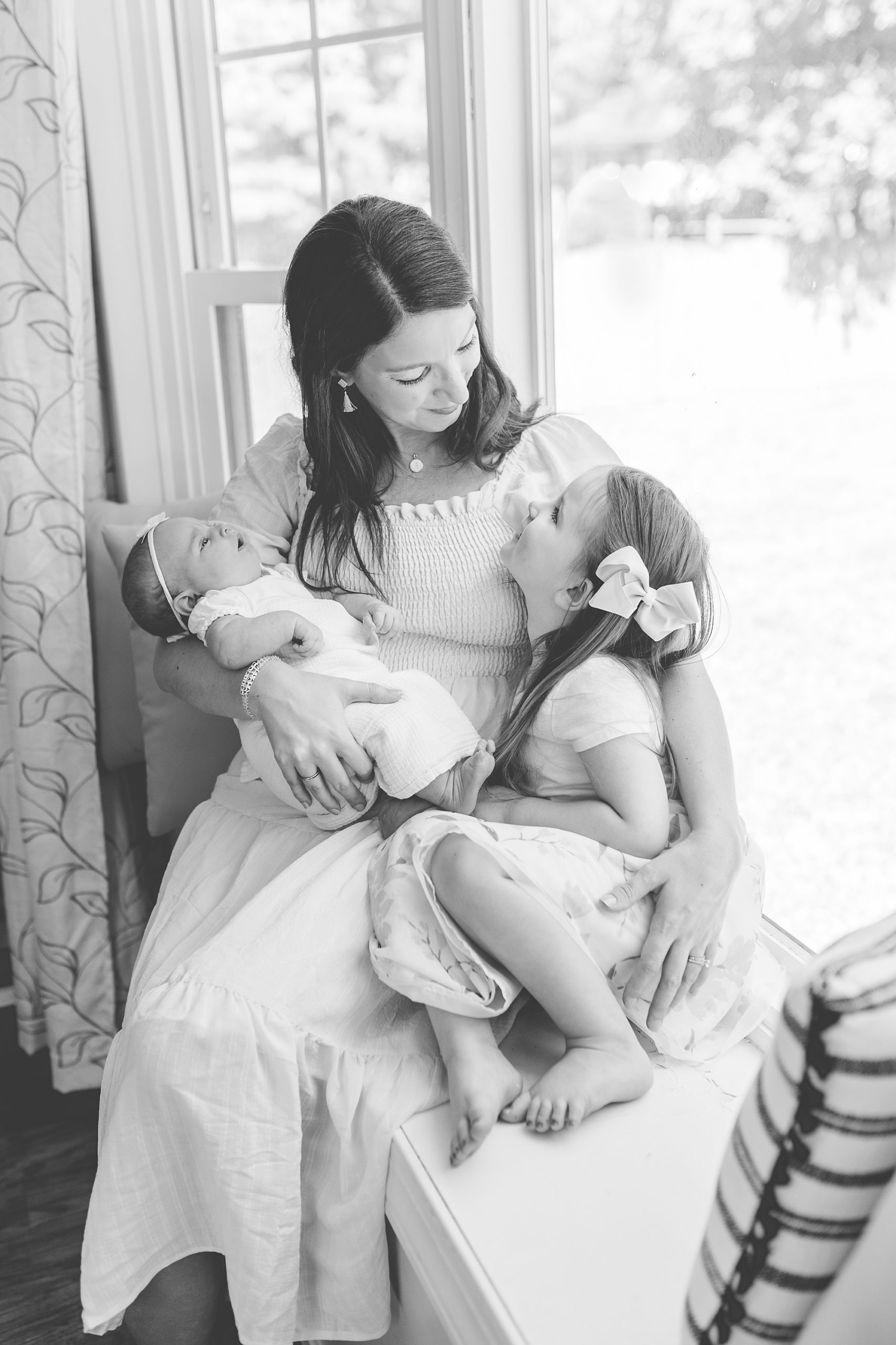 mom sits holding two daughters during Annapolis MD lifestyle newborn session