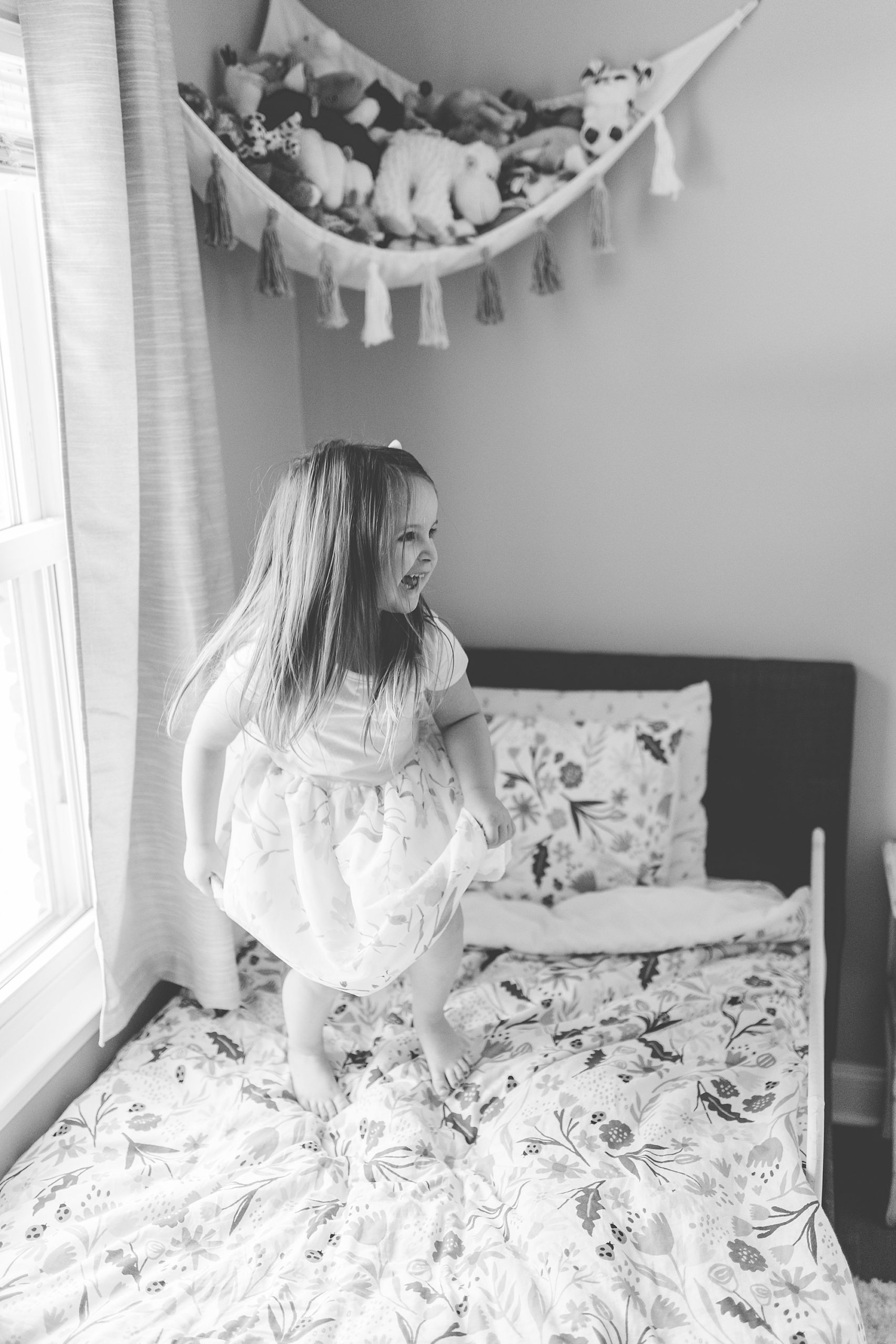 girl plays in bedroom during newborn photos at home for sister 