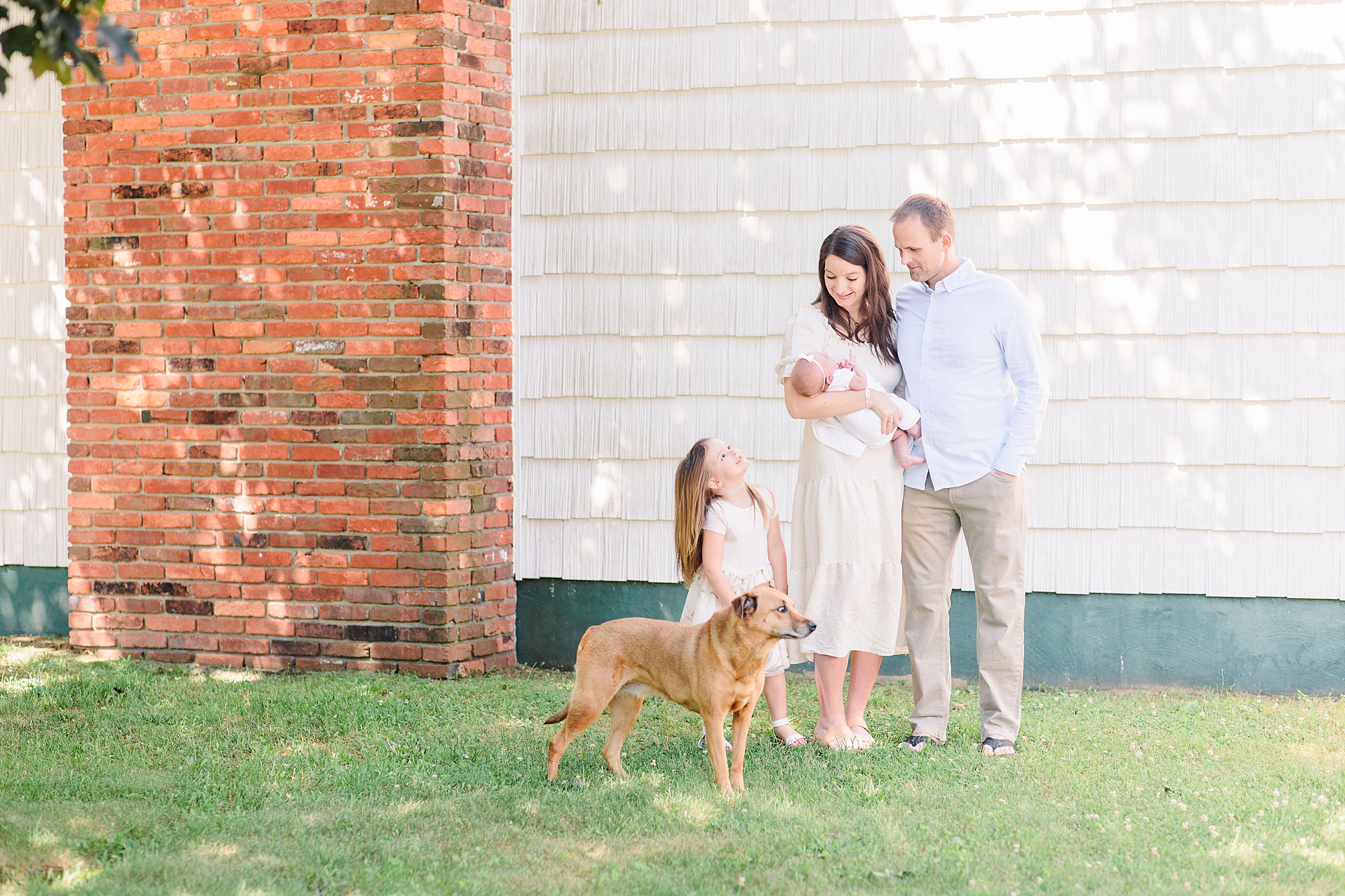 parents stand with two daughters and dog during Annapolis MD lifestyle newborn session