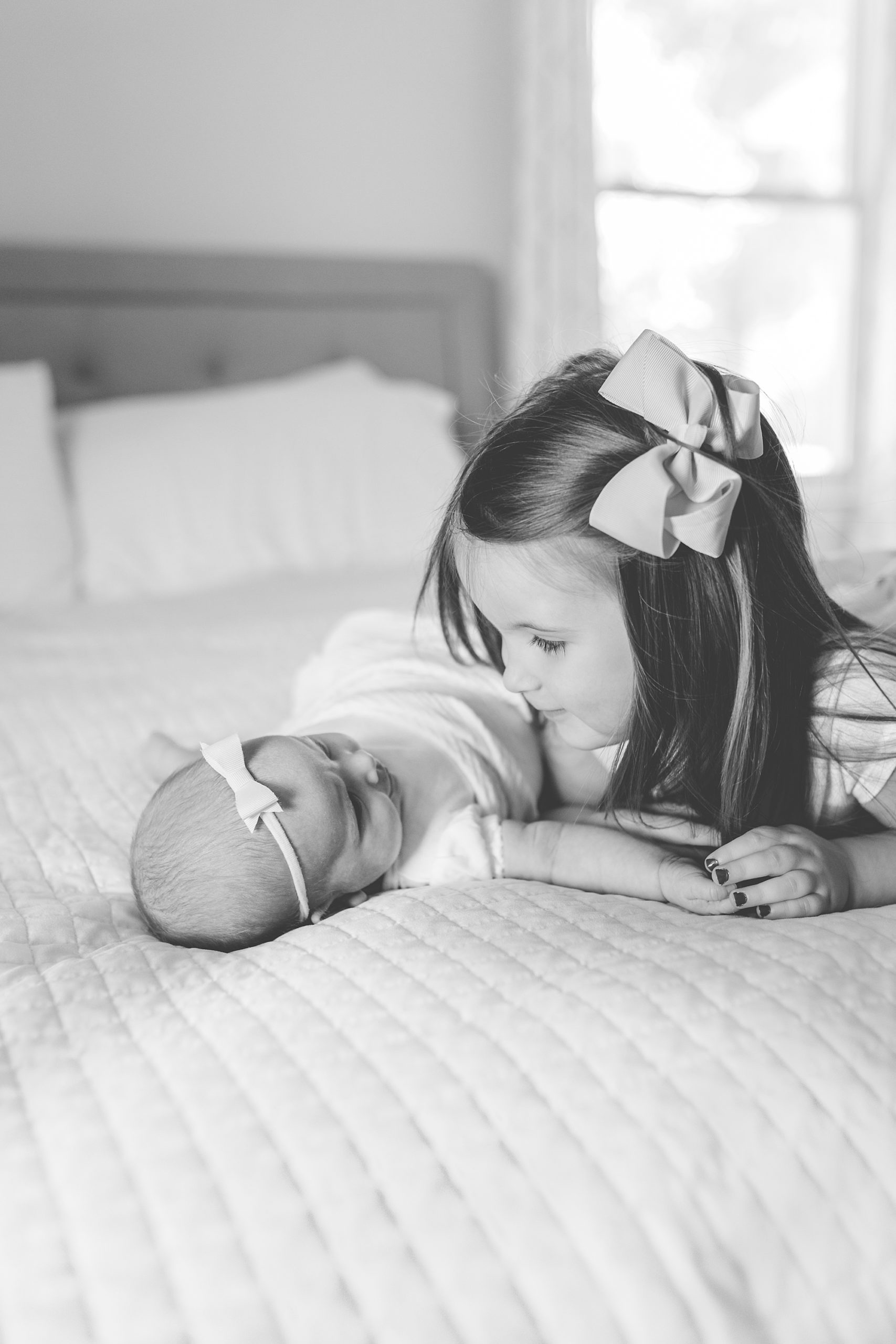 sister looks at newborn baby during lifestyle photos at home