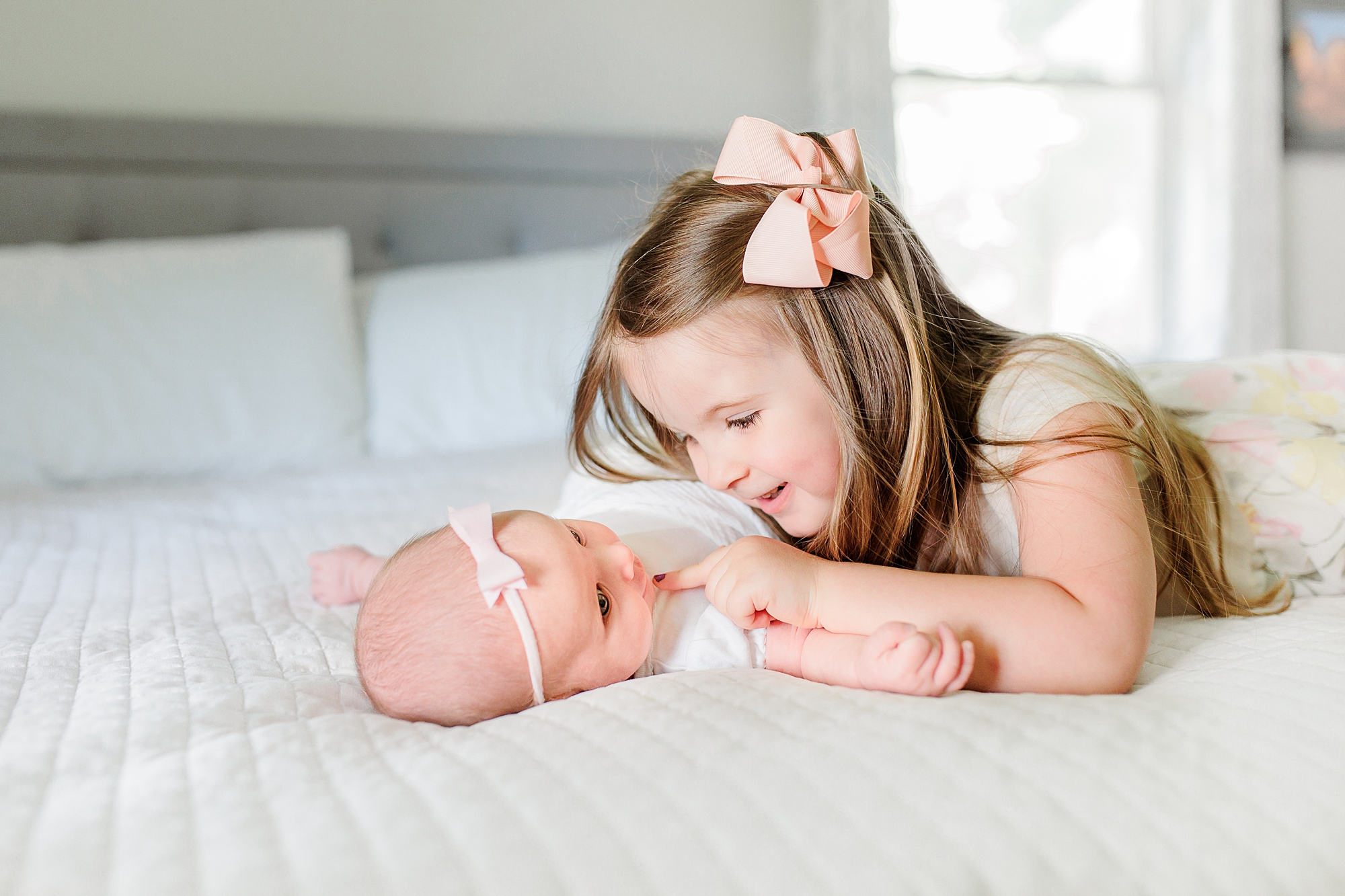 big sister looks down at little baby during Annapolis MD lifestyle newborn session