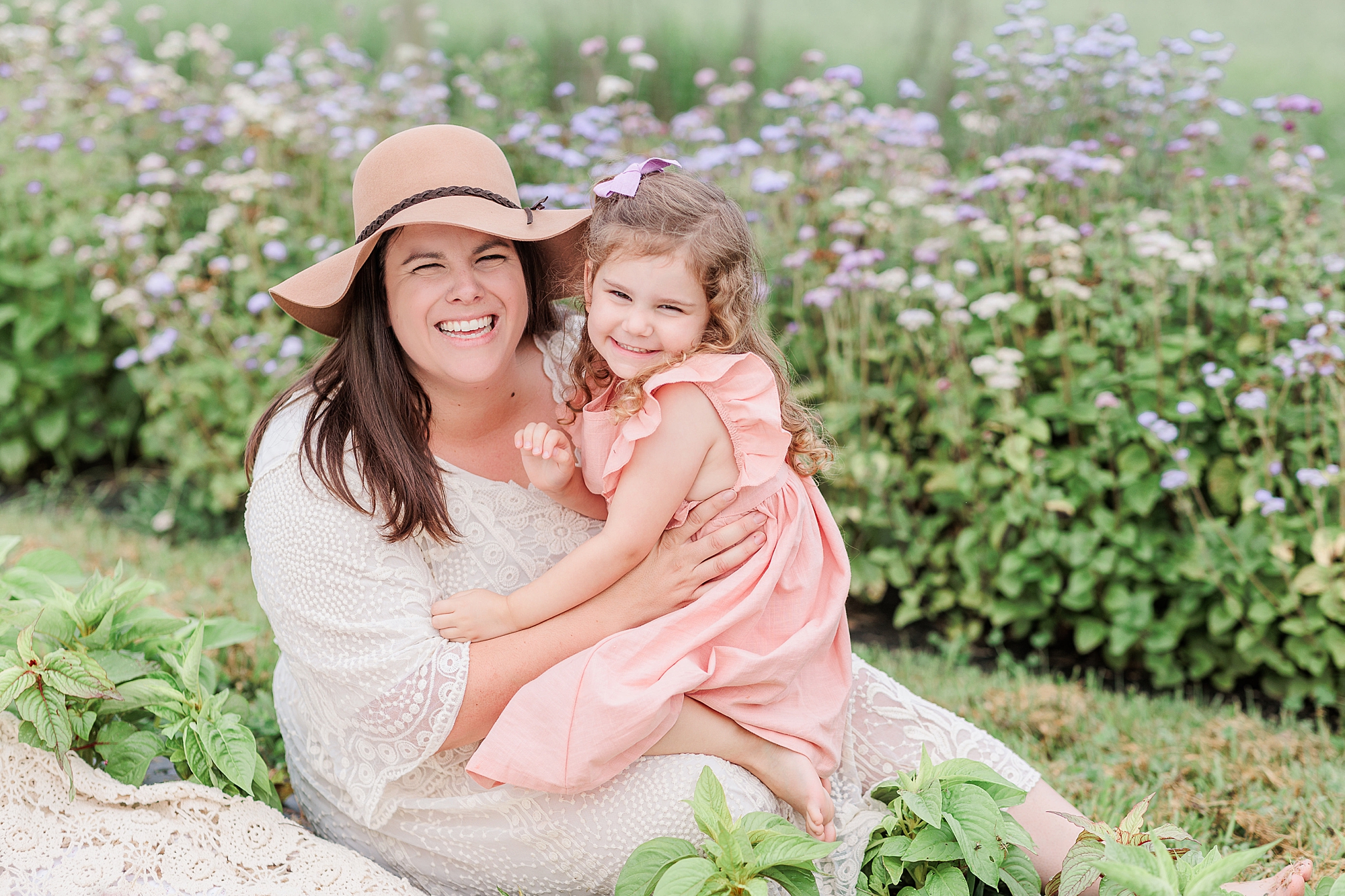 mom and daughter sit among wildflowers
