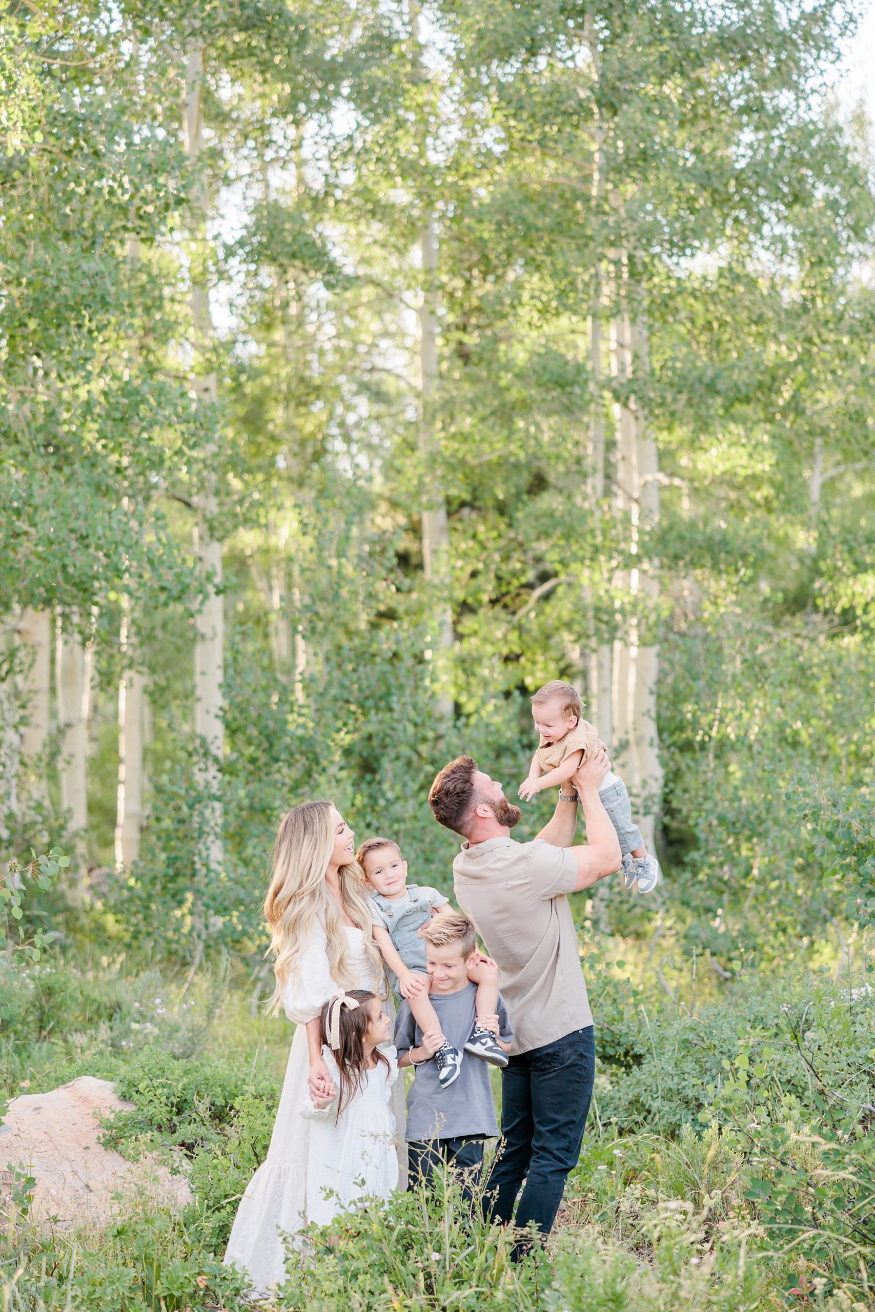 dad lifts son up during family photos in Utah woods