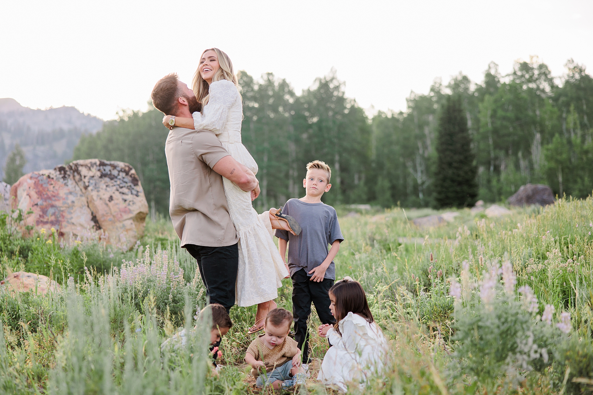 husband picks up wife during family photos 