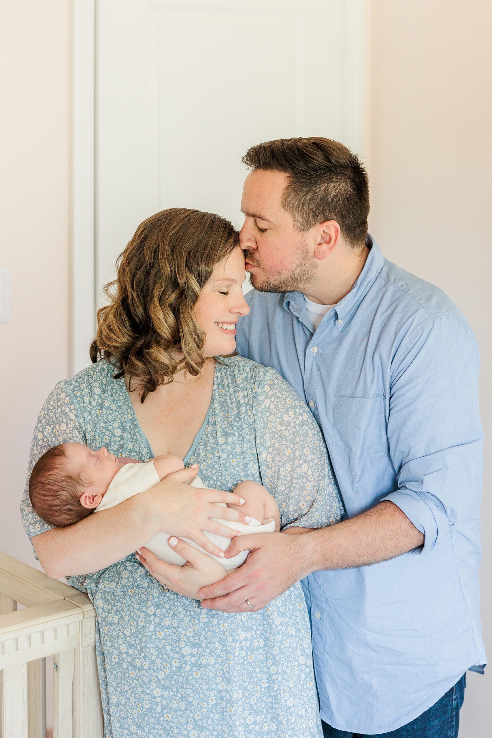 dad kisses mom's forehead during lifestyle newborn session at home