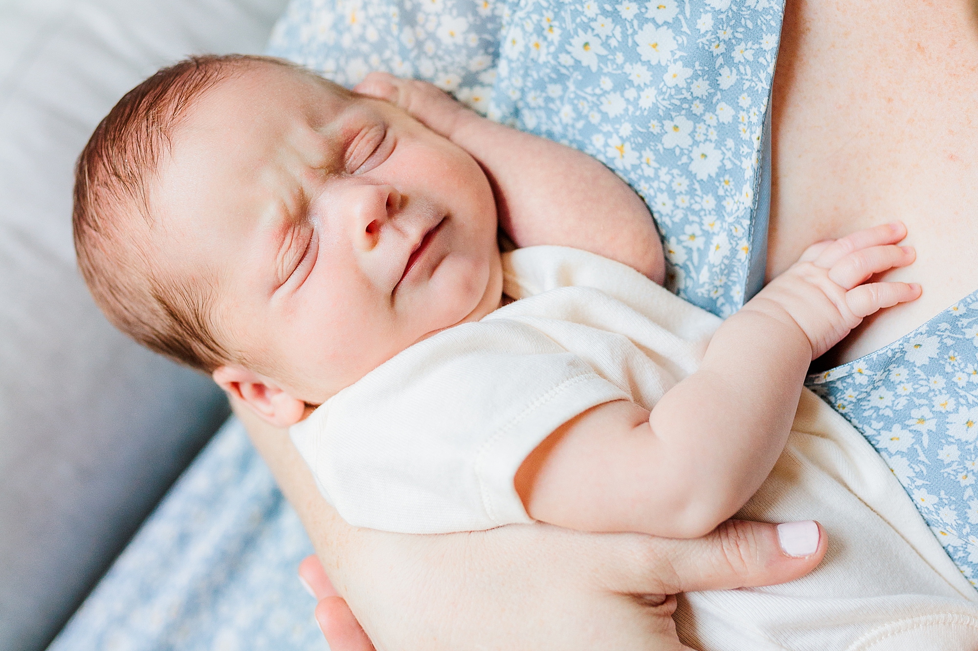 baby smiles laying on mom's chest during lifestyle newborn session