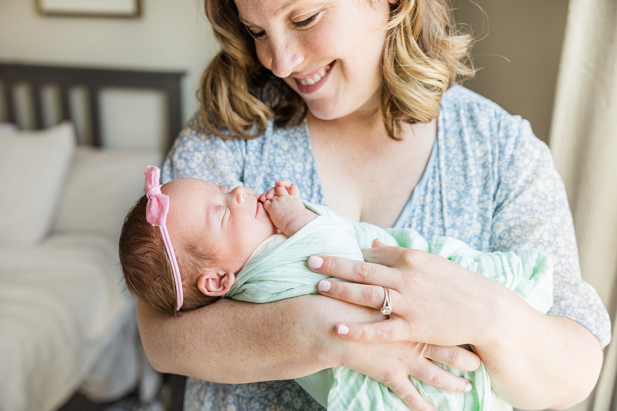 mom smiles at baby in green wrap during lifestyle newborn session in Anne Arundel Co. 