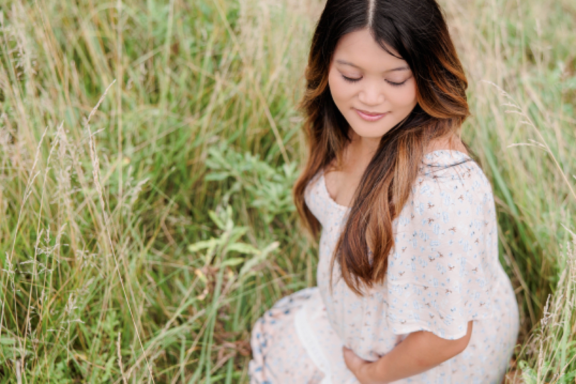 expecting mother sits in grass during maternity session