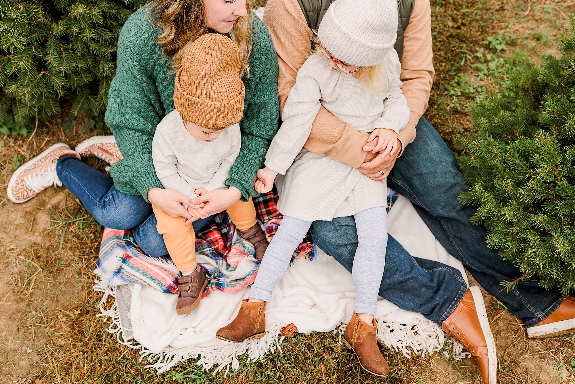 family hugs on blanket during holiday portraits at Christmas tree farm