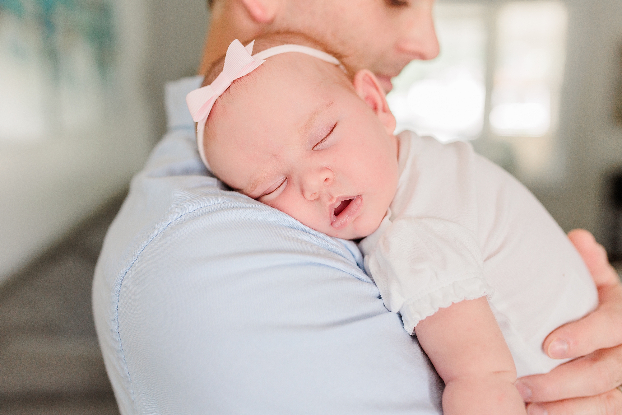 baby lays cheek on dad's shoulder during lifestyle portraits 
