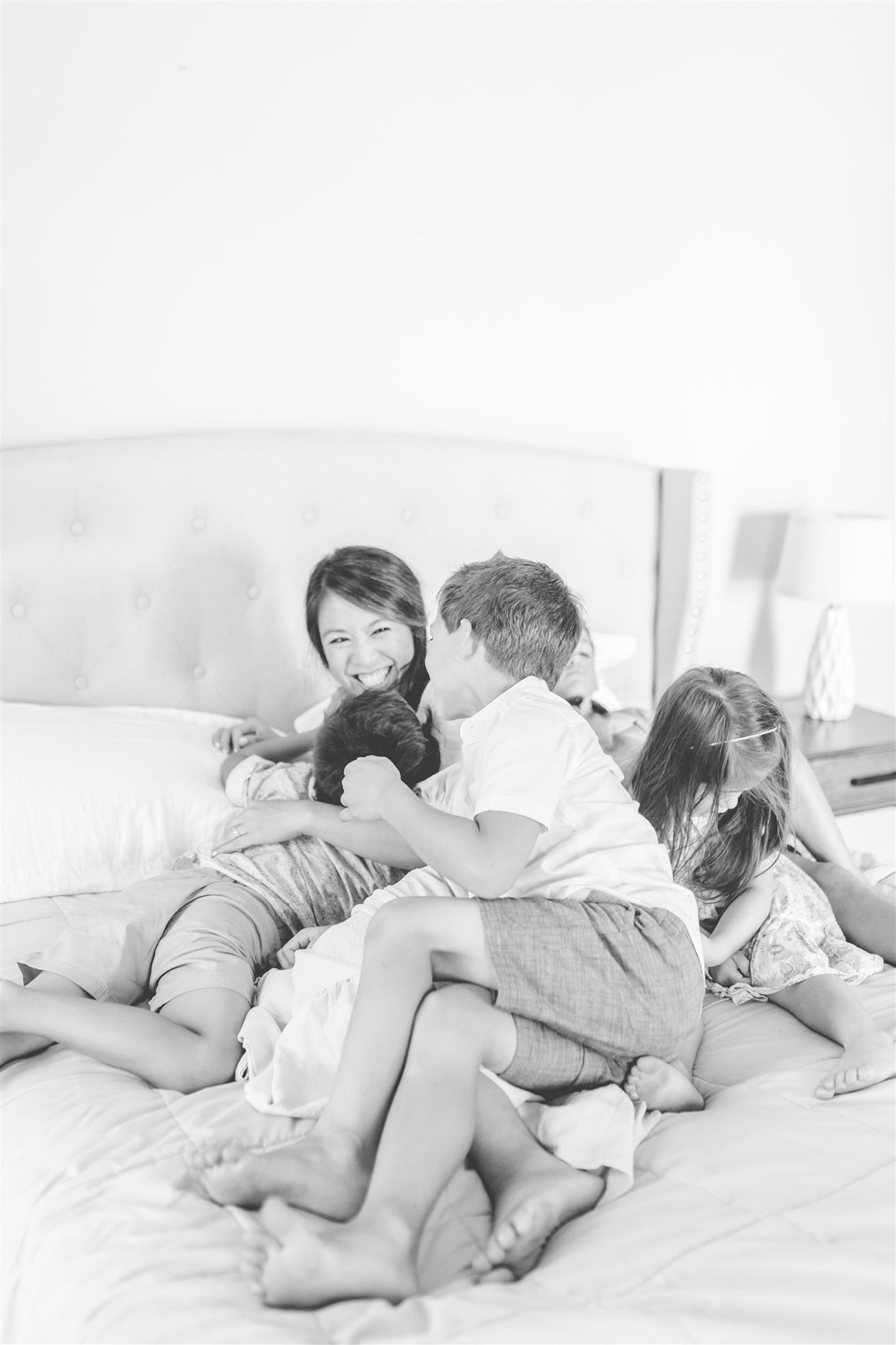 family plays together on bed during lifestyle family photos 