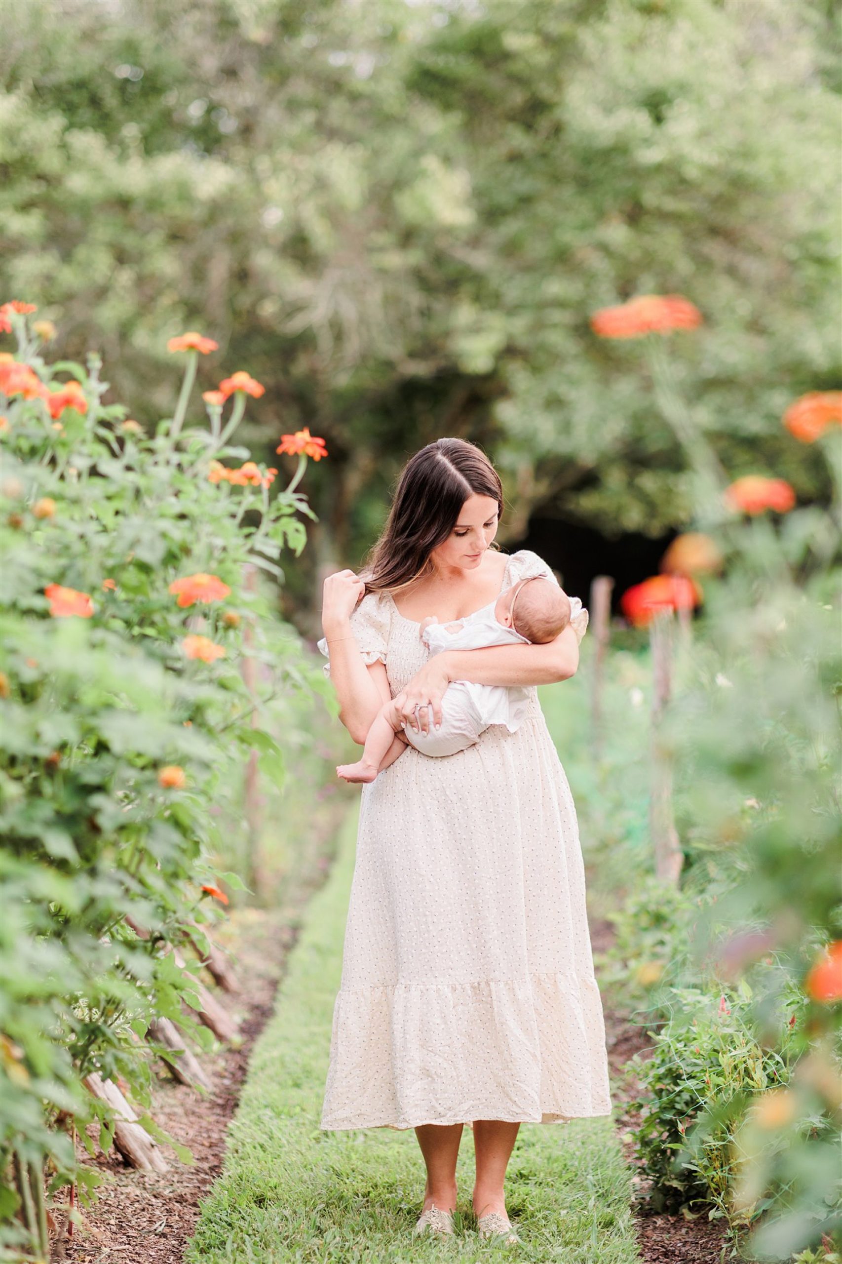 mom walks with baby through field of flowers