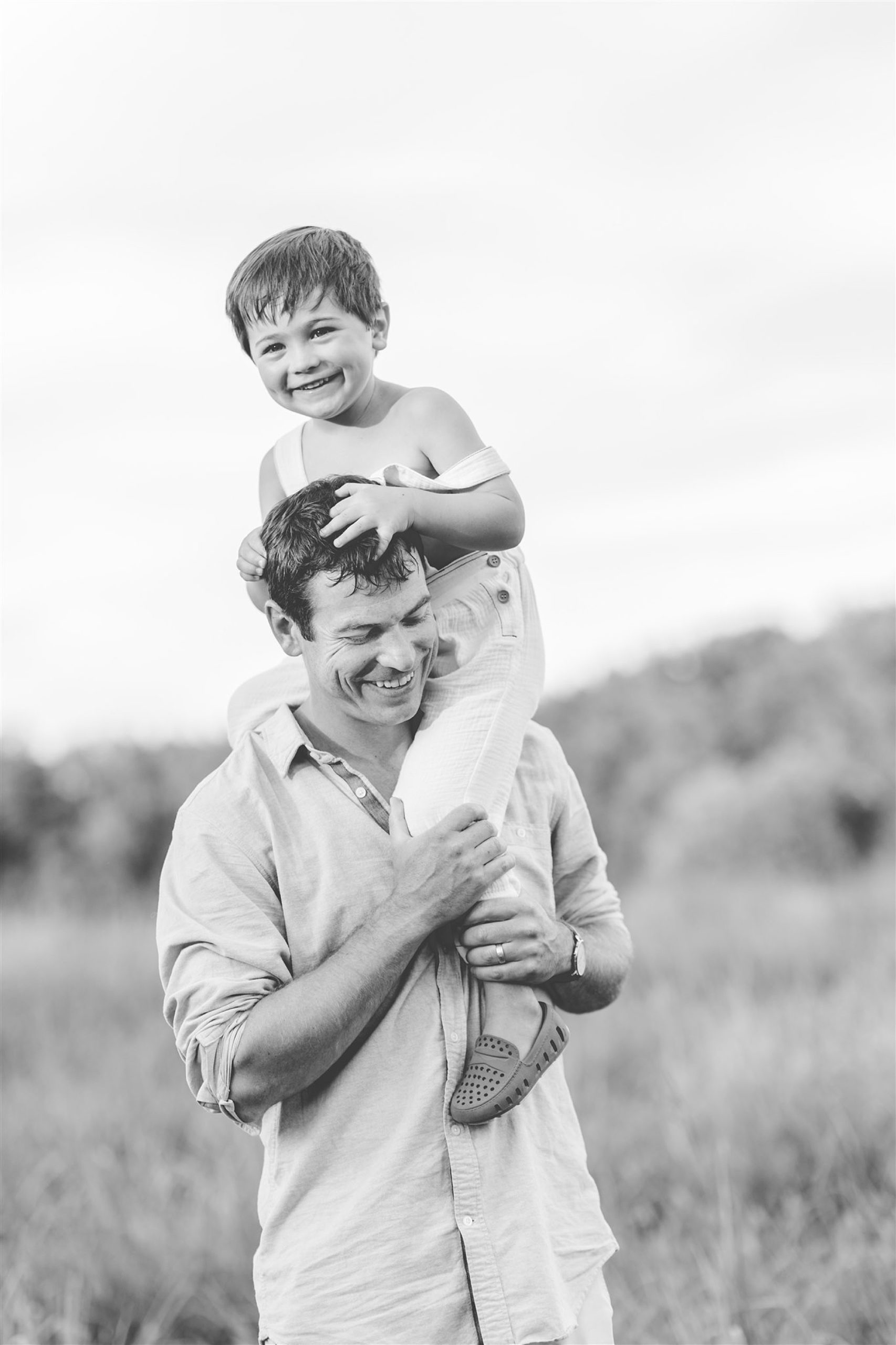 black and white portrait of dad with son on shoulders