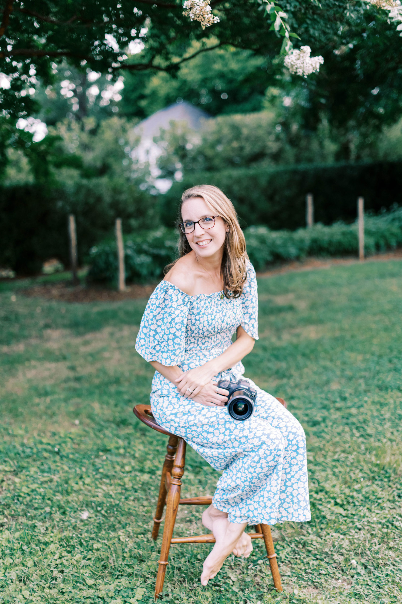 Virginia family photographer Christina Tundo sits on stool holding camera 