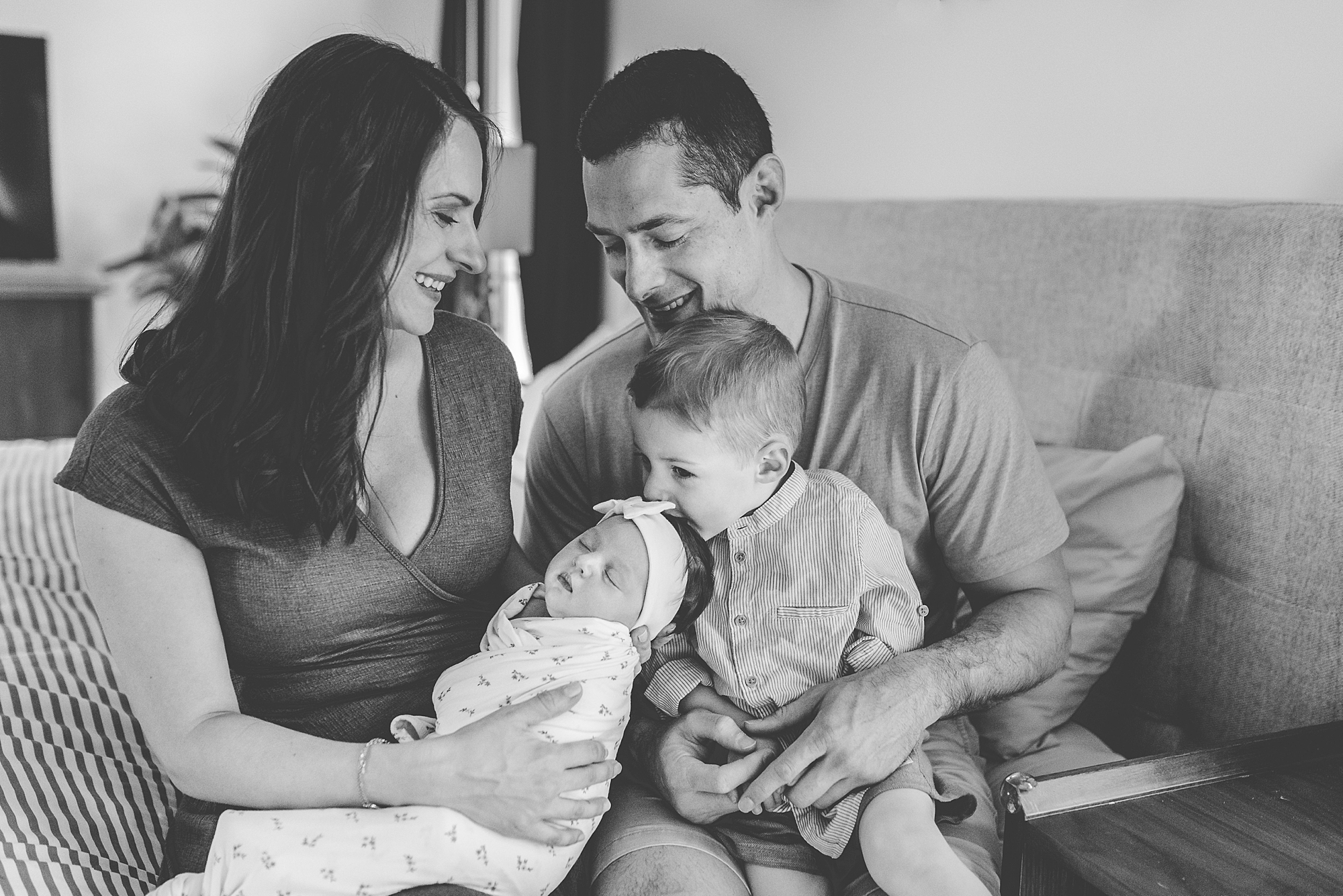 family of four sits on couch during Clarksville MD lifestyle newborn session