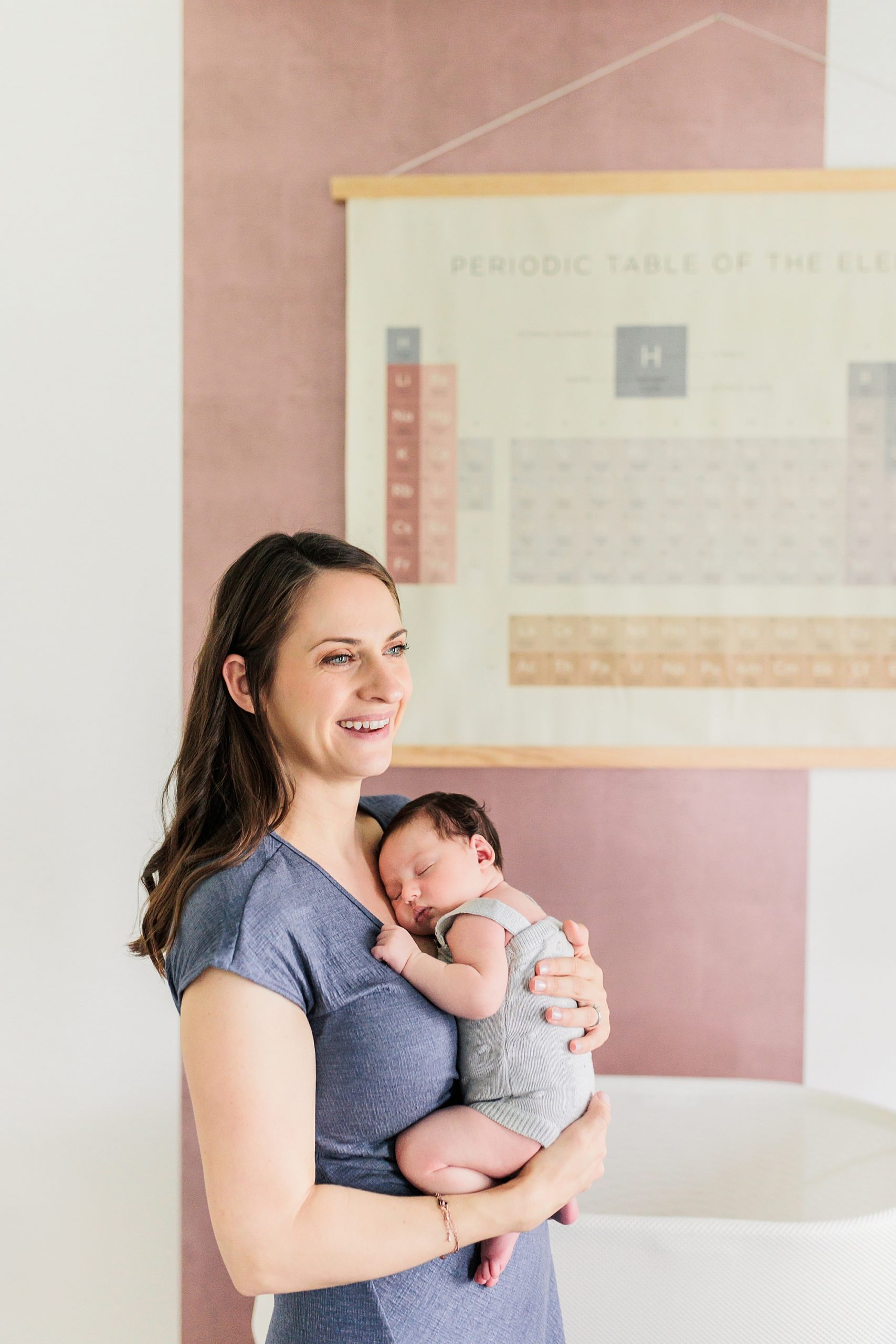 mom laughs smiling with baby girl by periodic table mural in room