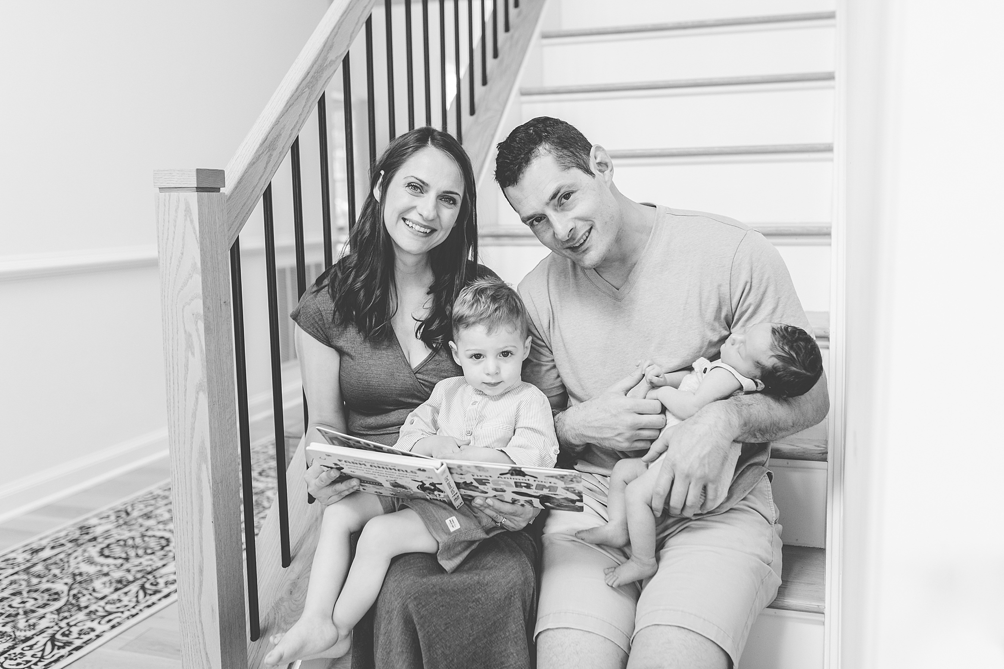 family sits on steps reading during Clarksville MD lifestyle newborn session