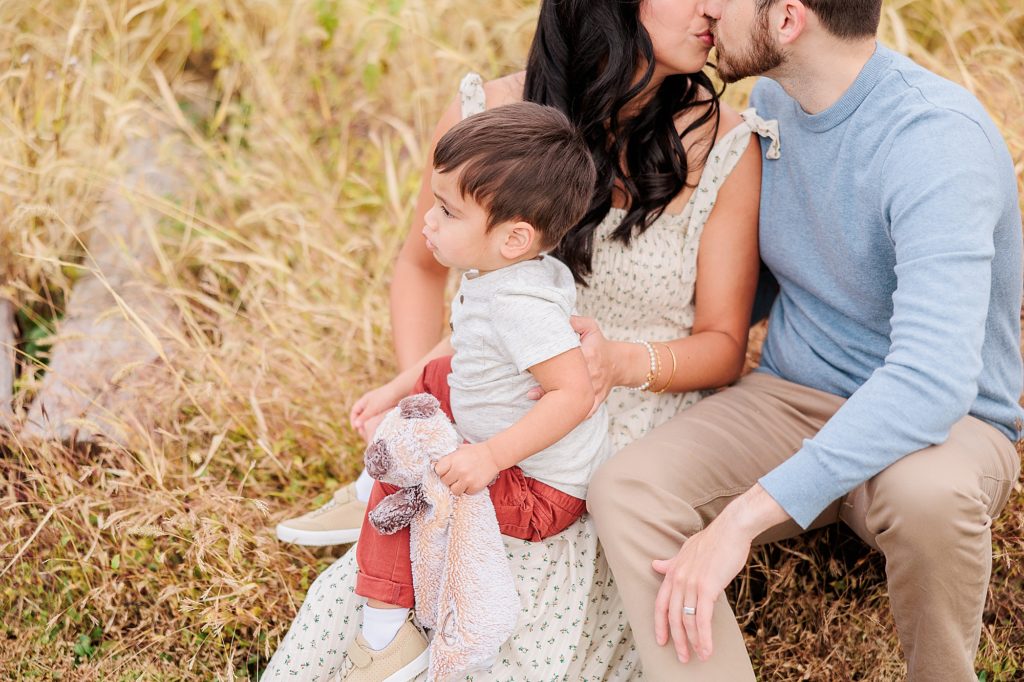 parents hold toddler son on lap during family photos in Maryland field