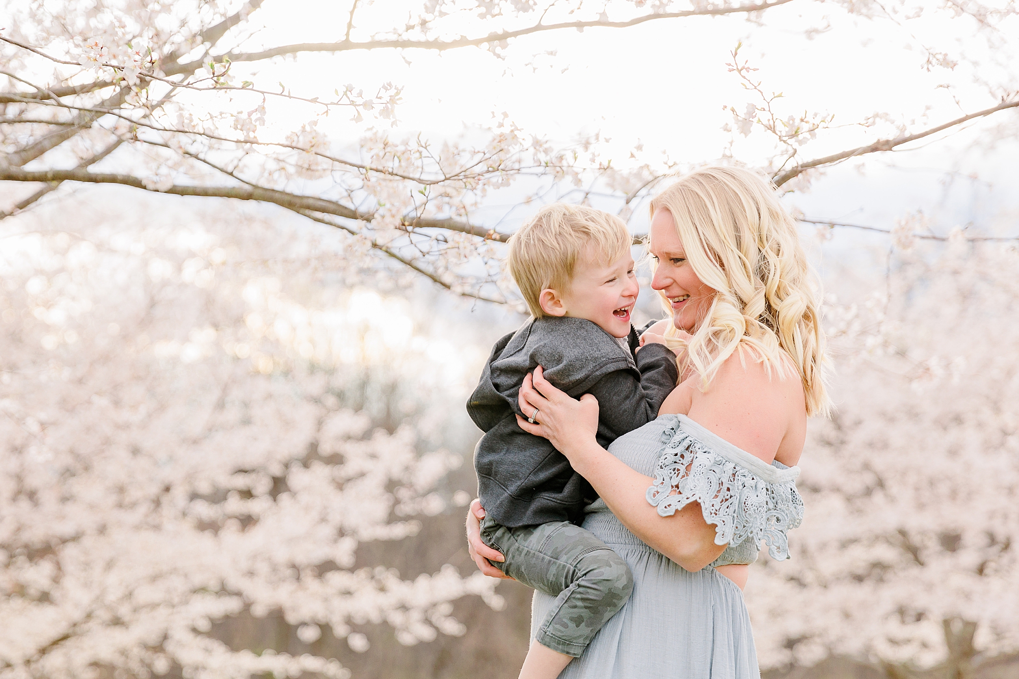 mom in off-the-shoulder blue gown hugs son during Howard County family portraits