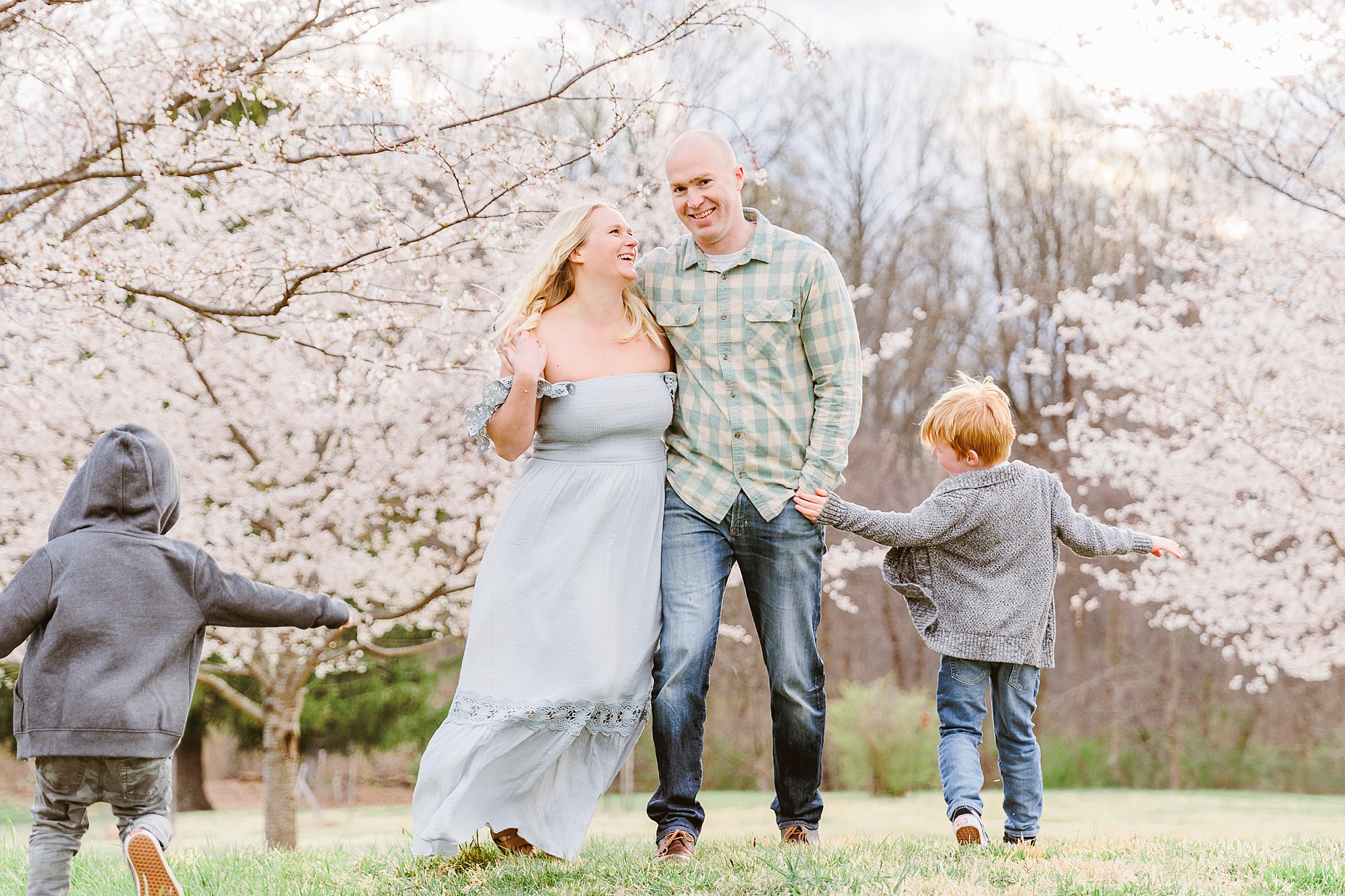 woman smiles up at husband while sons run around them during Howard County family portraits