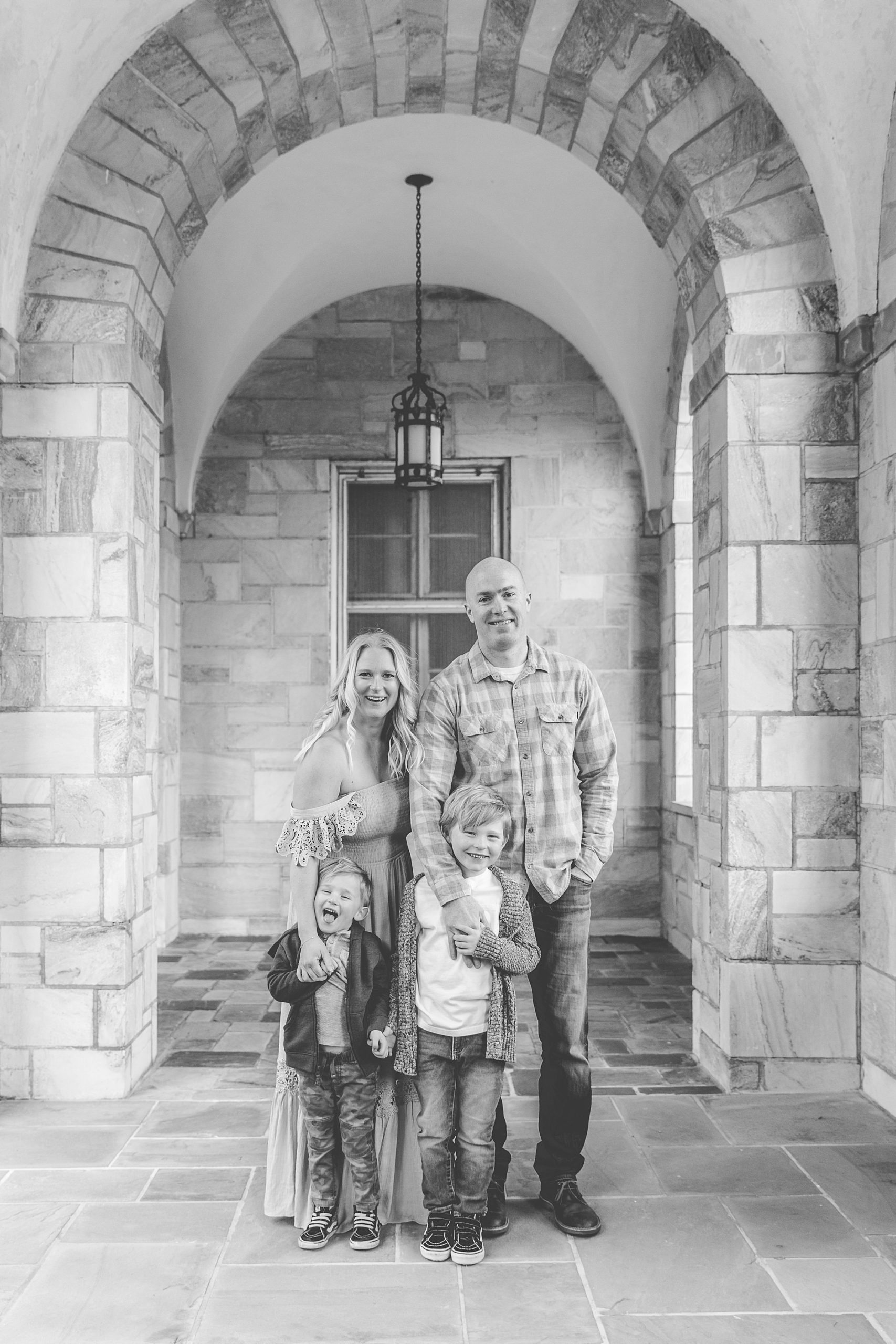 family of four hugs under stone archway in Maryland 