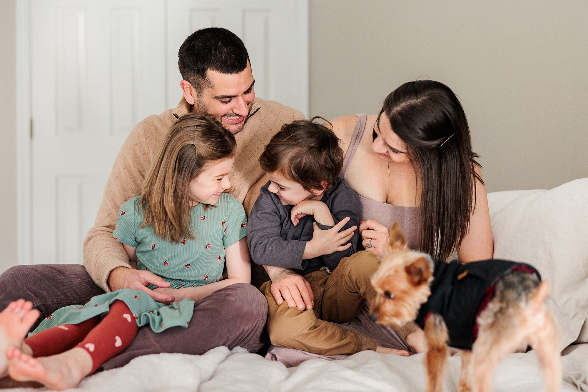 family sits on bed with kids and go during lifestyle family photos