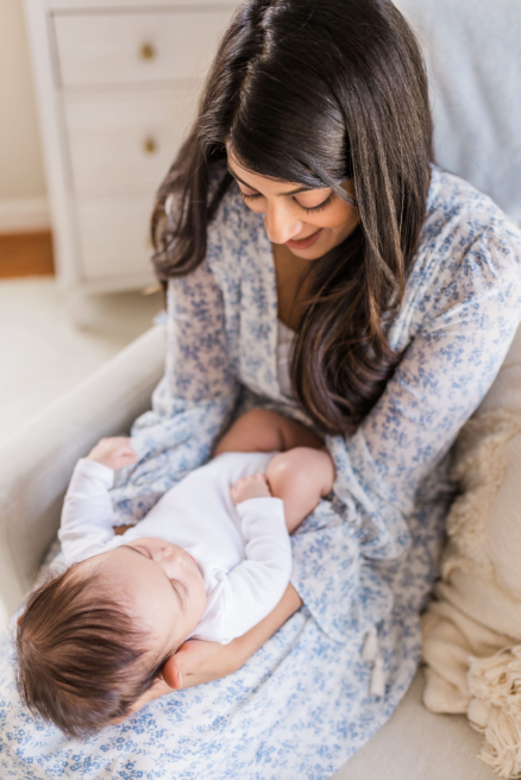 mom holds baby in white onesie during lifestyle newborn session
