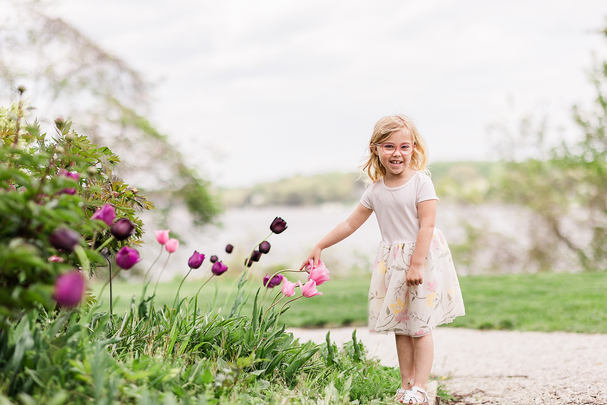 little girl points at pink flowers during family photos