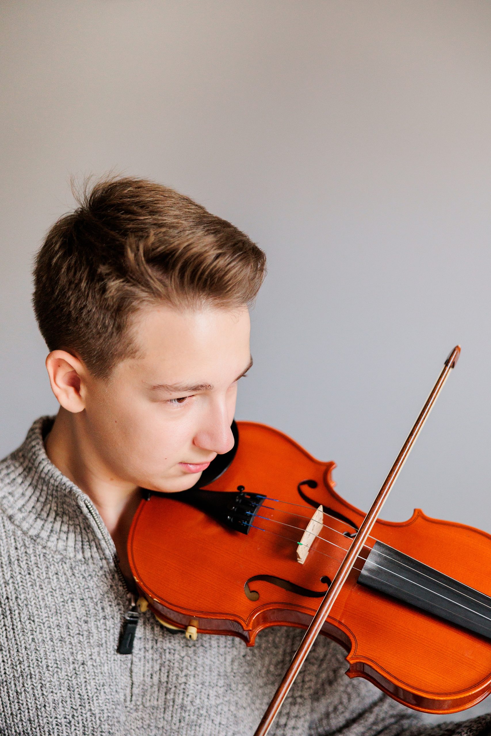 boy plays violin during family photos at home 