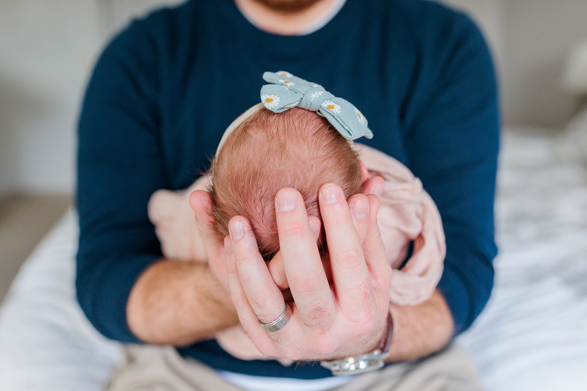 dad holds newborn baby girl in front of chest during lifestyle newborn session 