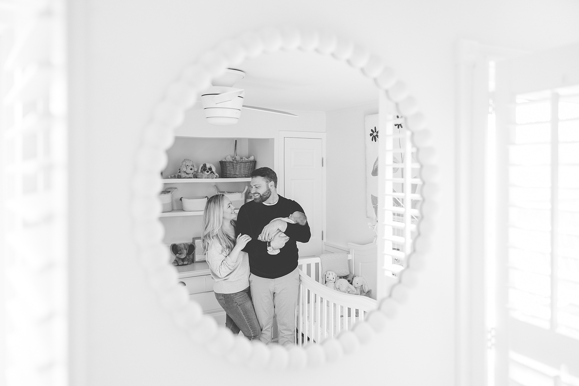 couple holds new baby girl in nursery reflected in mirror 