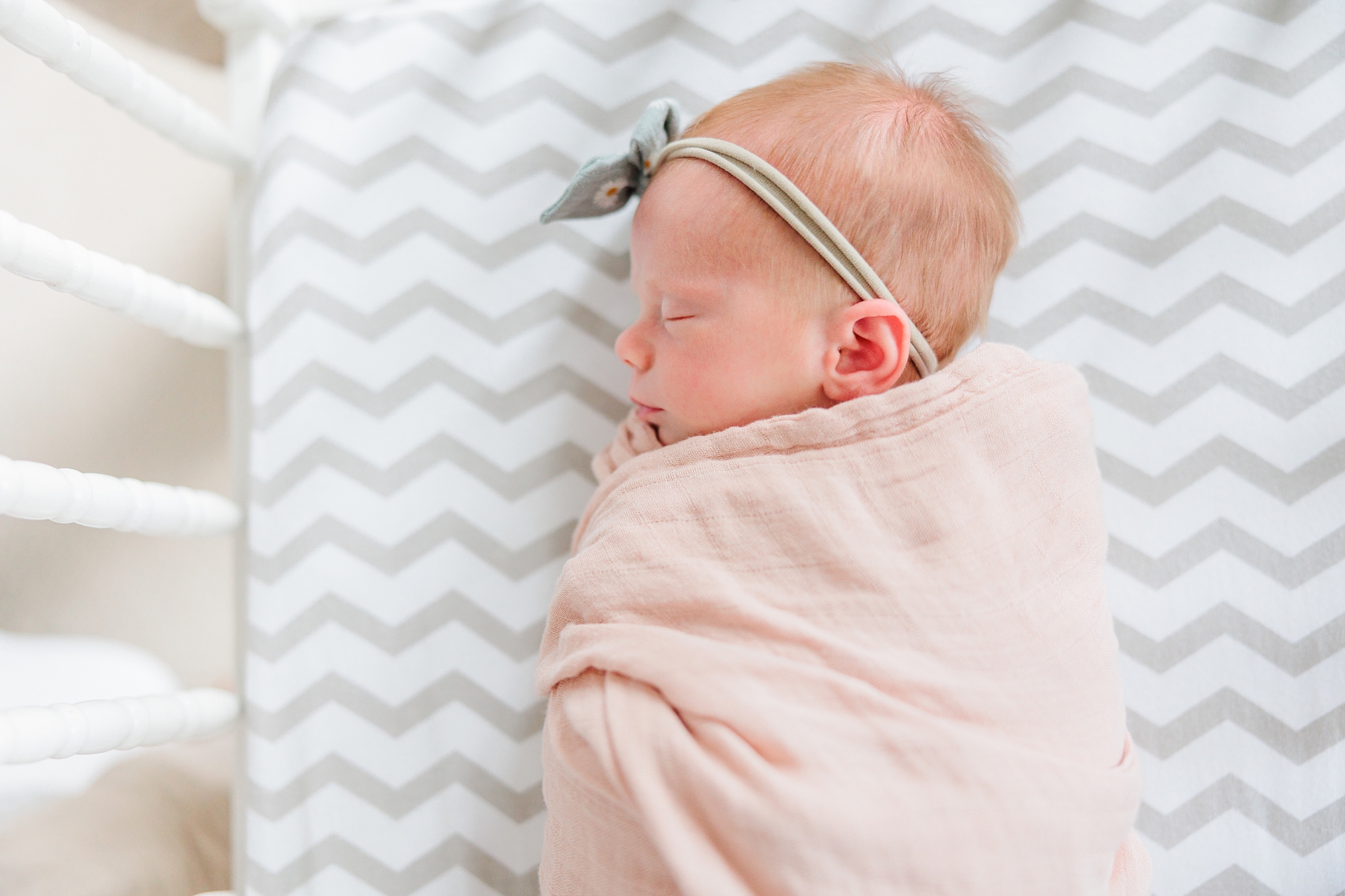 baby girl sleeps in pale pink blanket with green bow